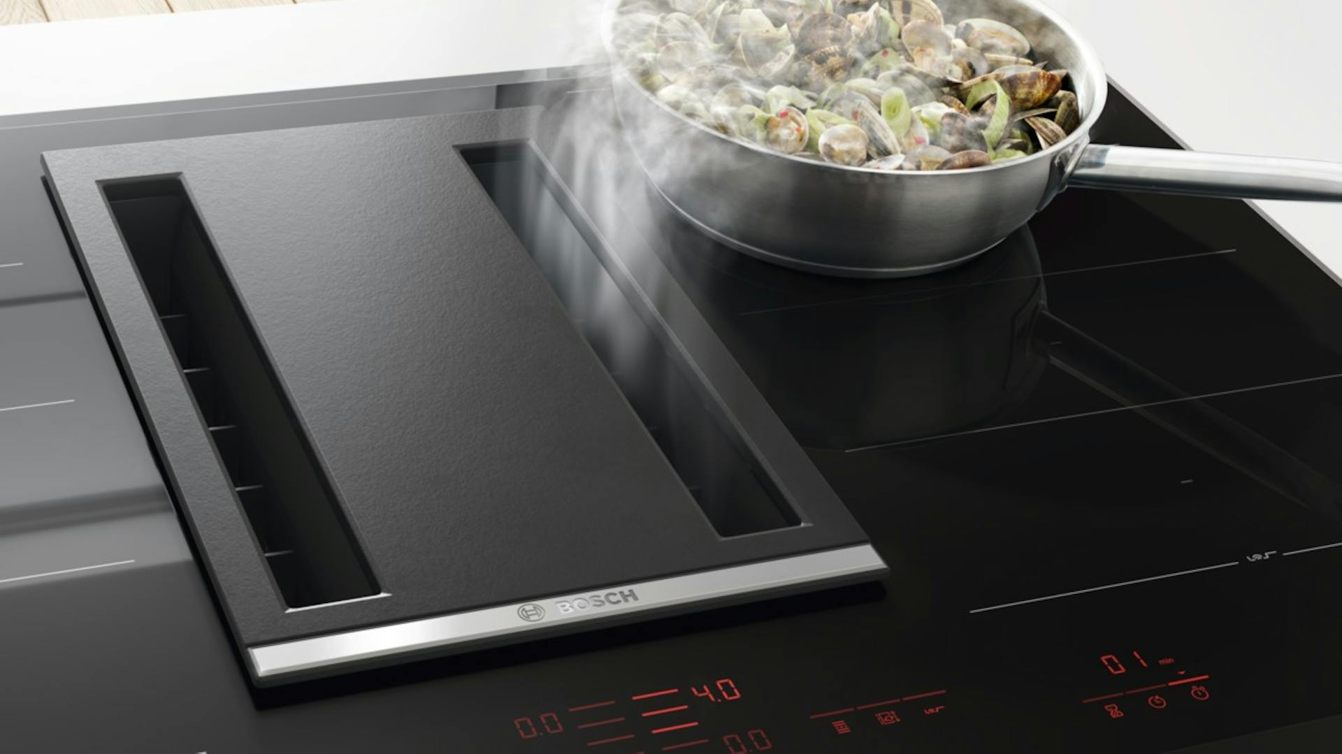 Ein Down Draft System zieht den Dunst von einem kochenden Gericht auf der Herdplatte in die Mulde ein.