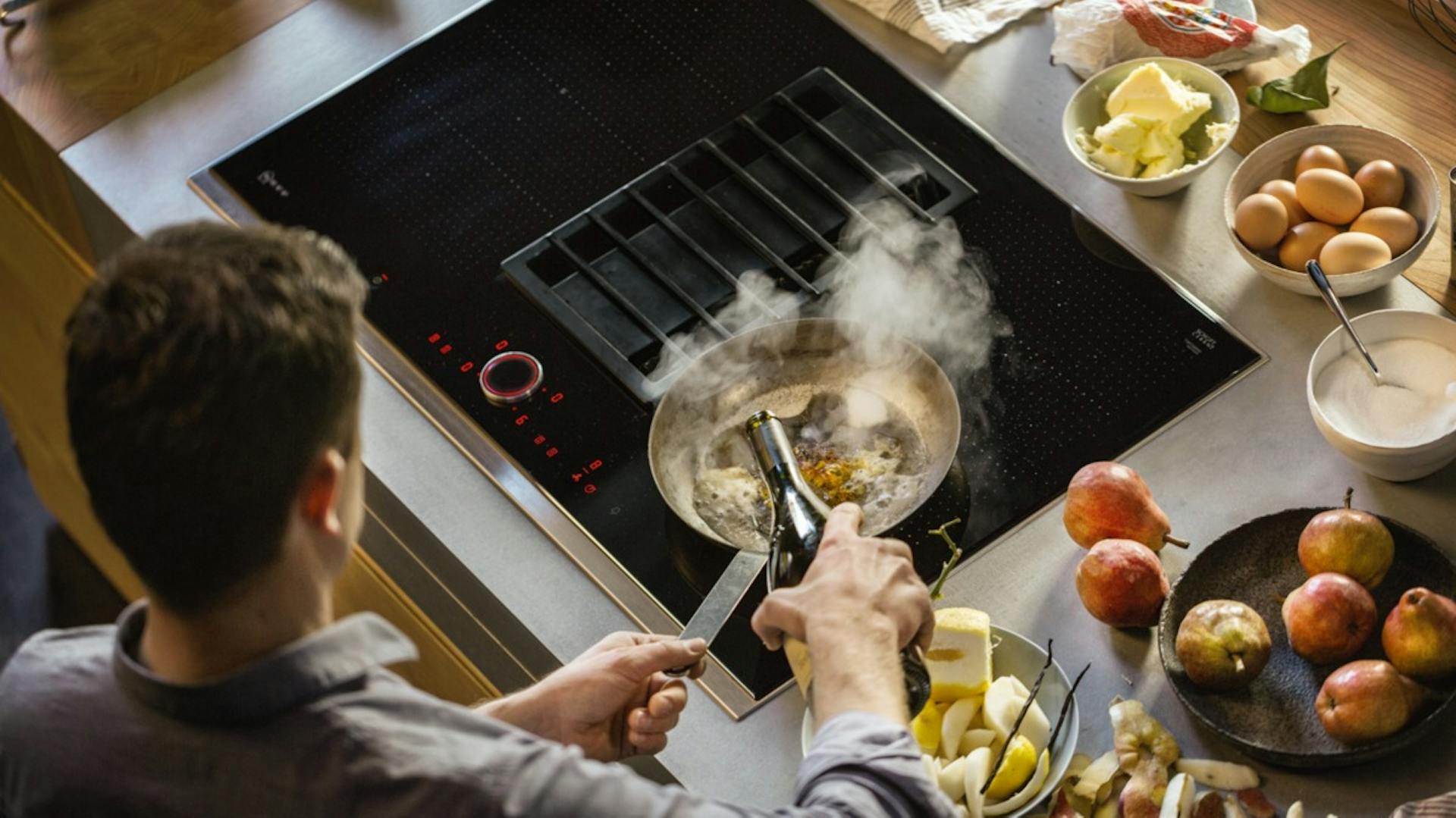 Person kocht auf Kochfeld mit integriertem Dunstabzug