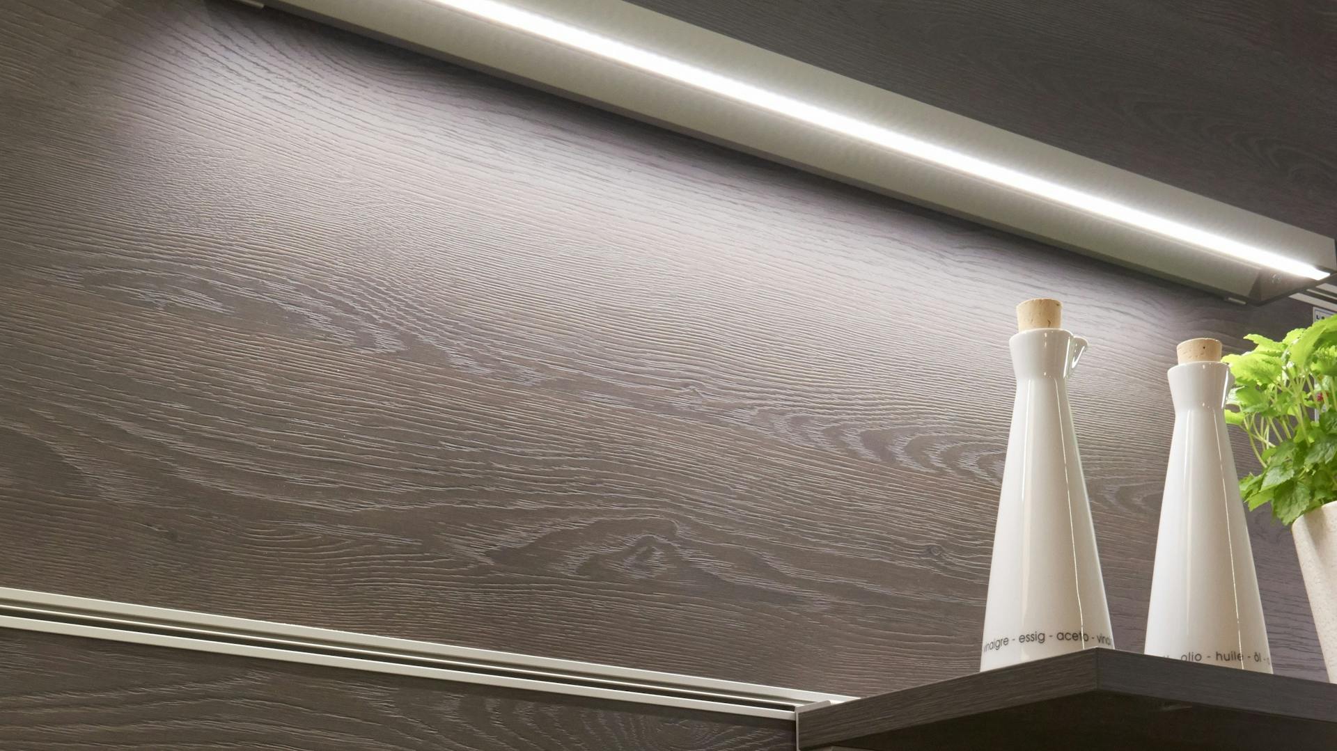 Ein Küchenregal wird von Wandleuchte beleuchtet.