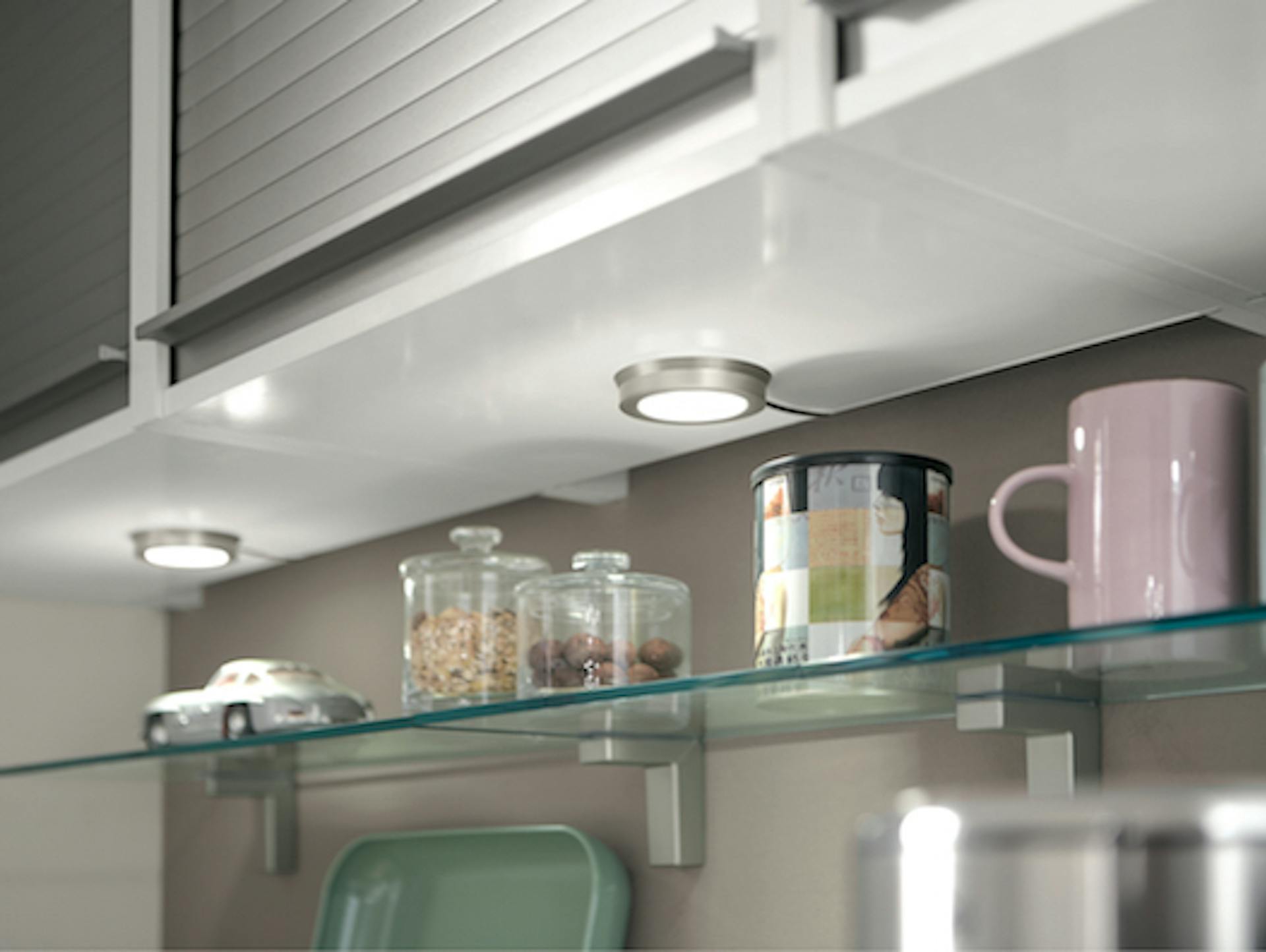 Küchenunterbauleuchten unter einem Oberschrank auf einem Regal mit Vorratsgläsern und Tassen.
