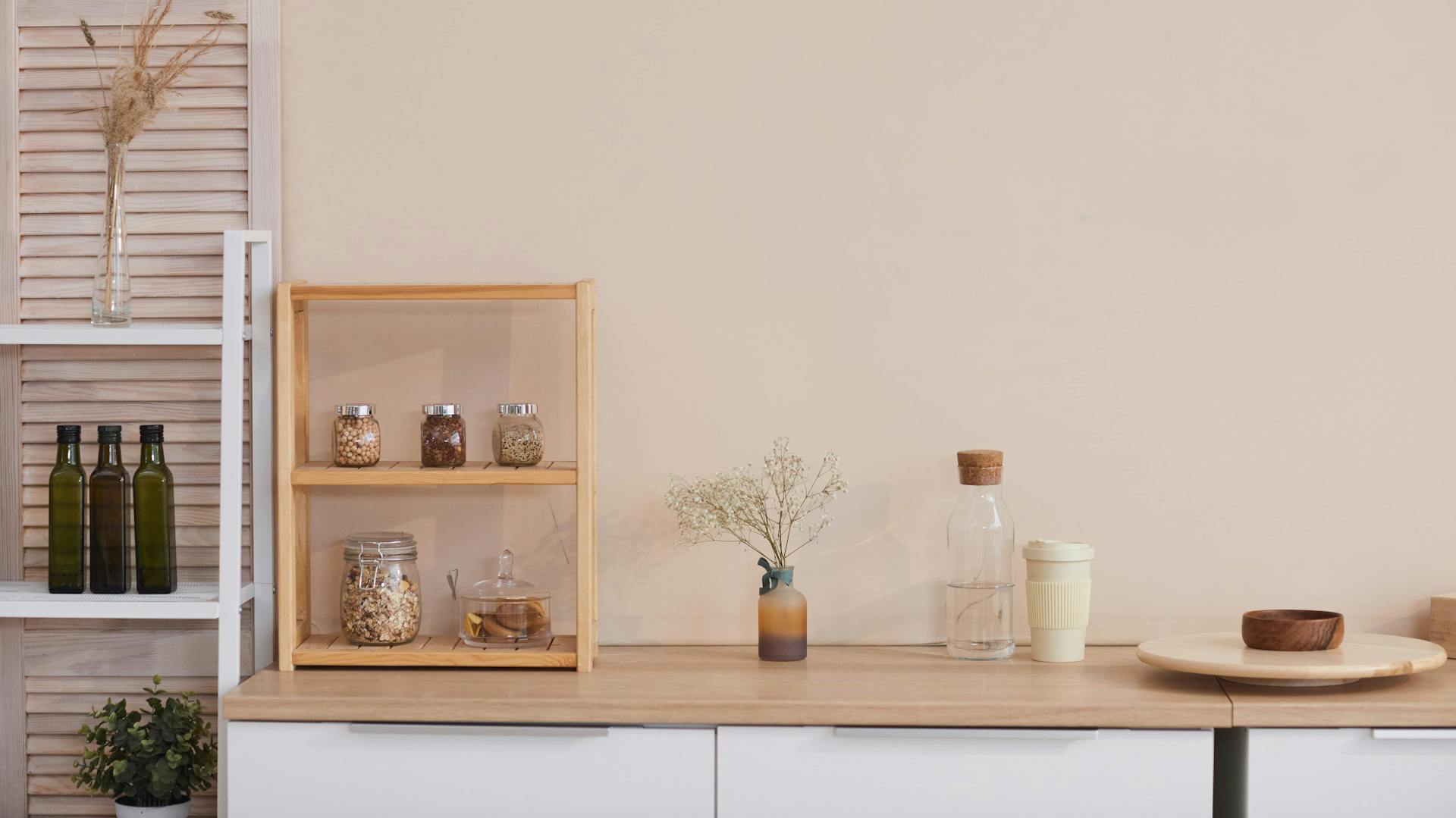 Hellbraune Wand, davor eine weiße Küchenzeile mit Holz-Arbeitsplatte und Küchenutensilien.