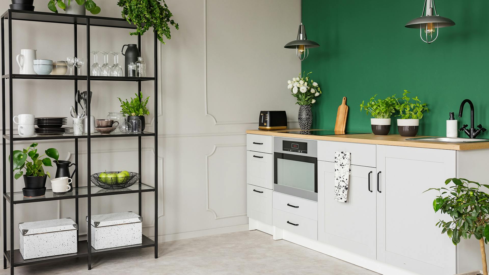 Metallregal und helle Küchenzeile vor grüner Wand.