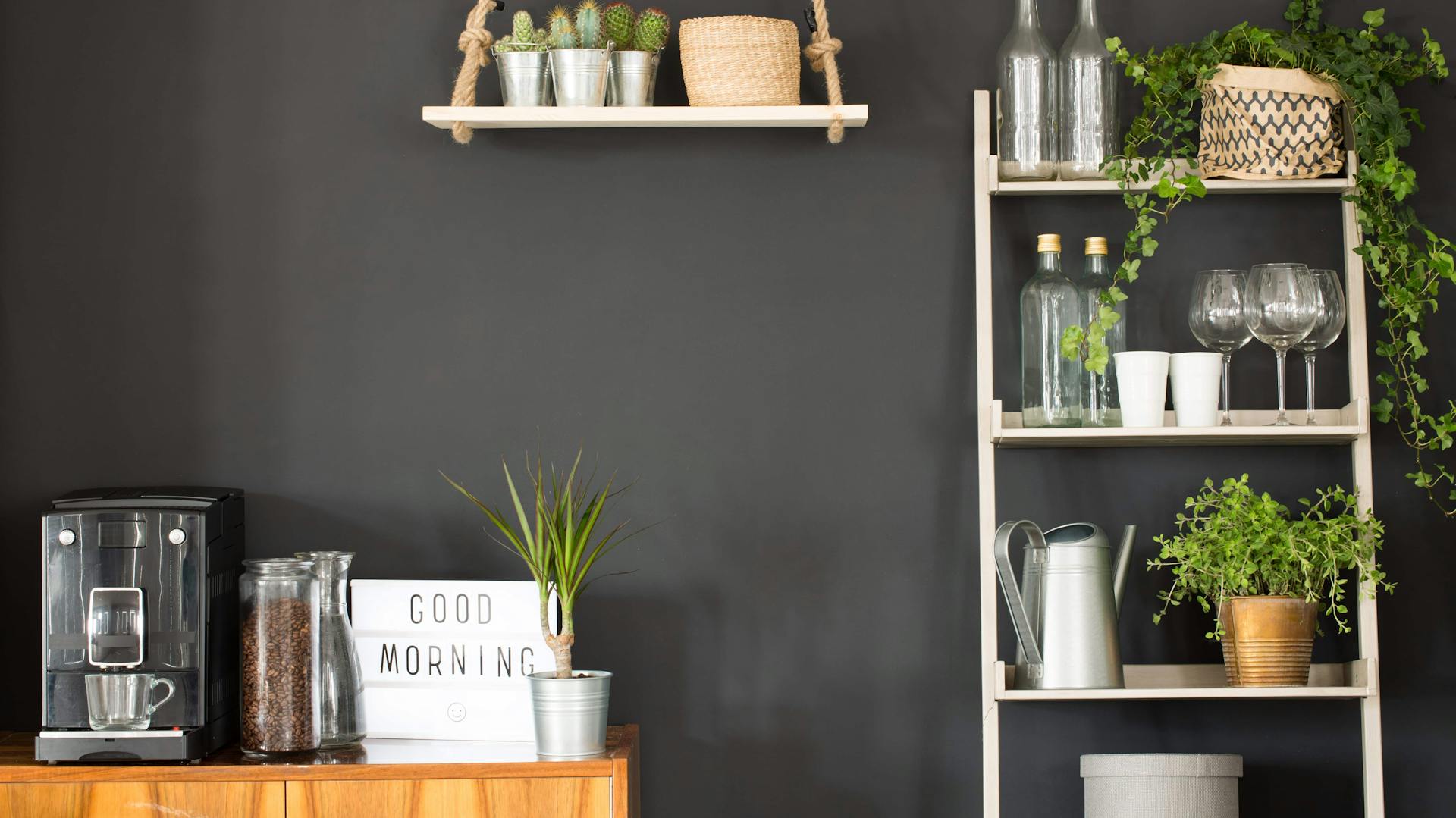 Küchenutensilien und Regale vor einer schwarzen Wand.