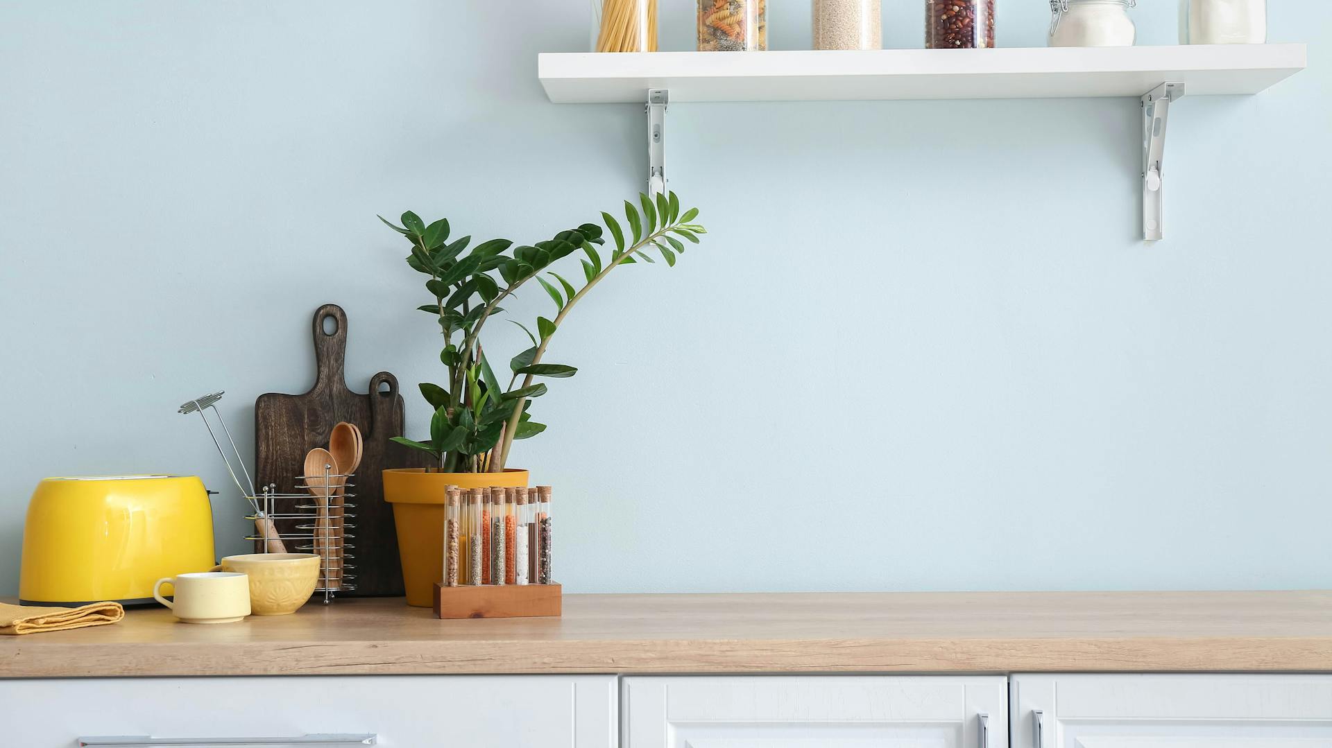 Türkisfarbener Waschtisch auf Fliesenboden mit Schachbrettmuster. Daneben eine grüne Pflanze in weißem Topf.