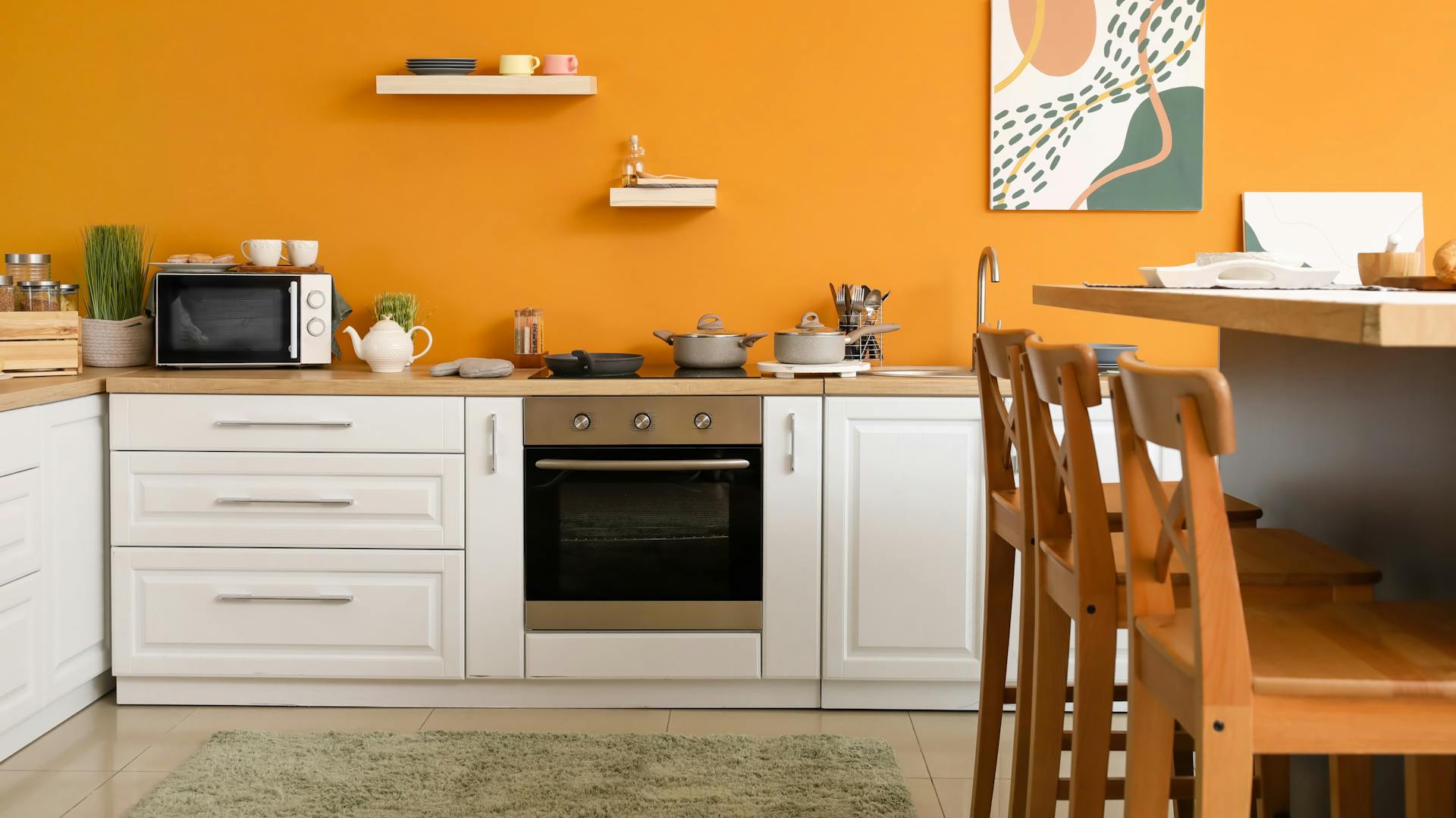 Weiße Küchenzeile vor einer orangen Wand.