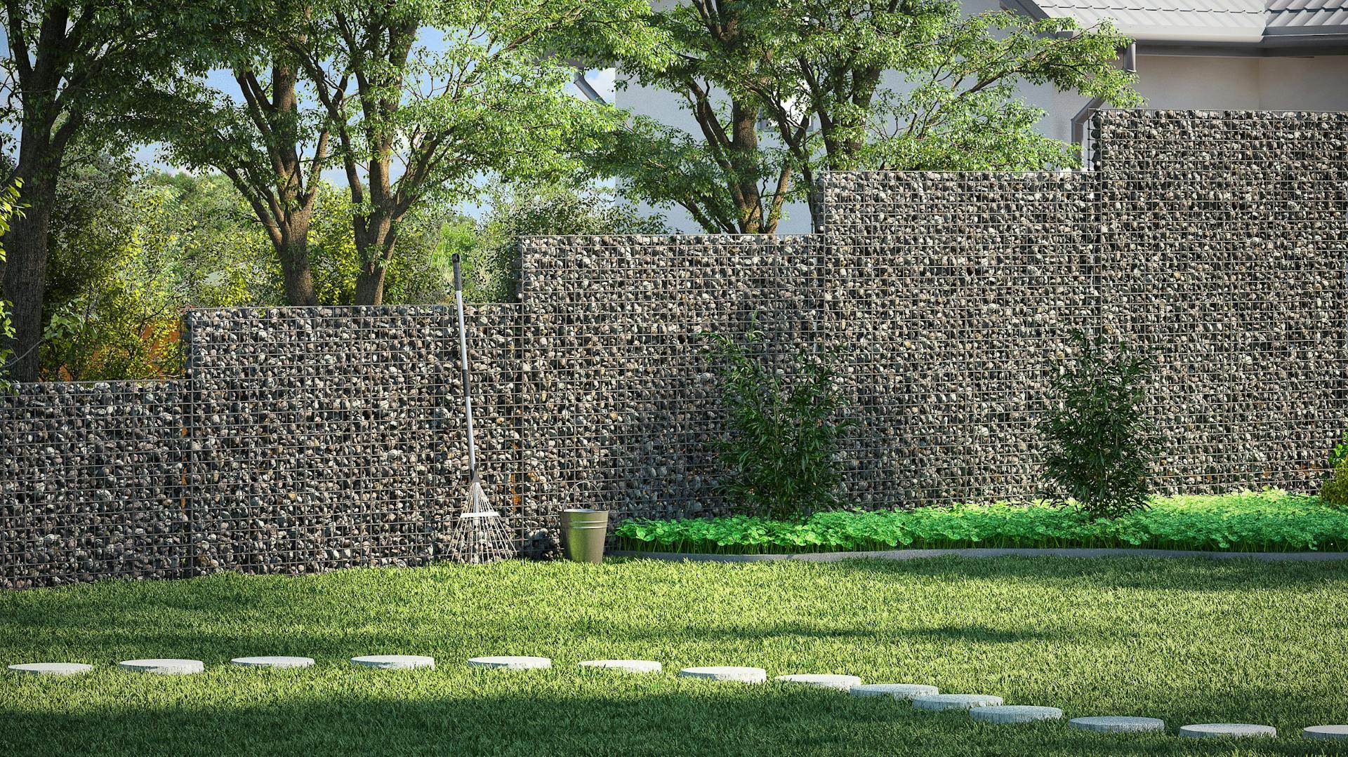 Gabione mit dunklen Steinen im Garten