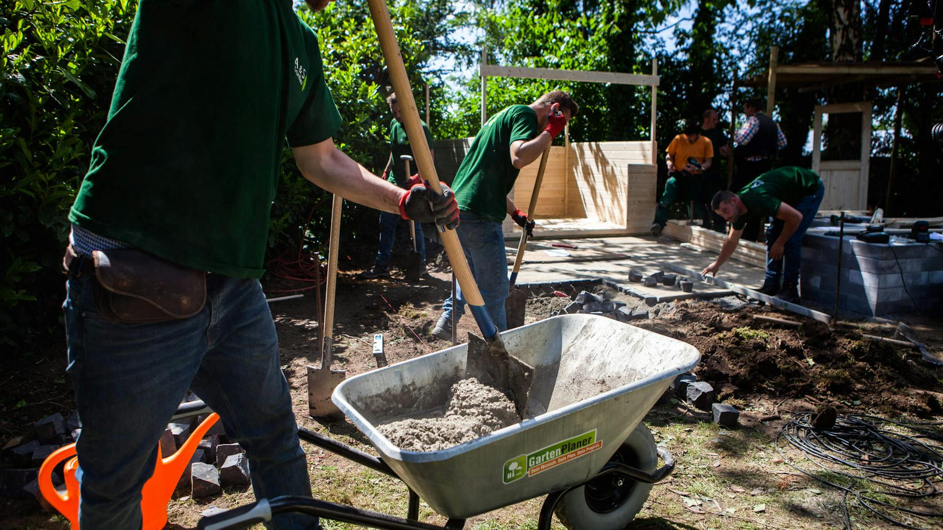 Handwerker mit Spaten und Schubkarre mit Beton