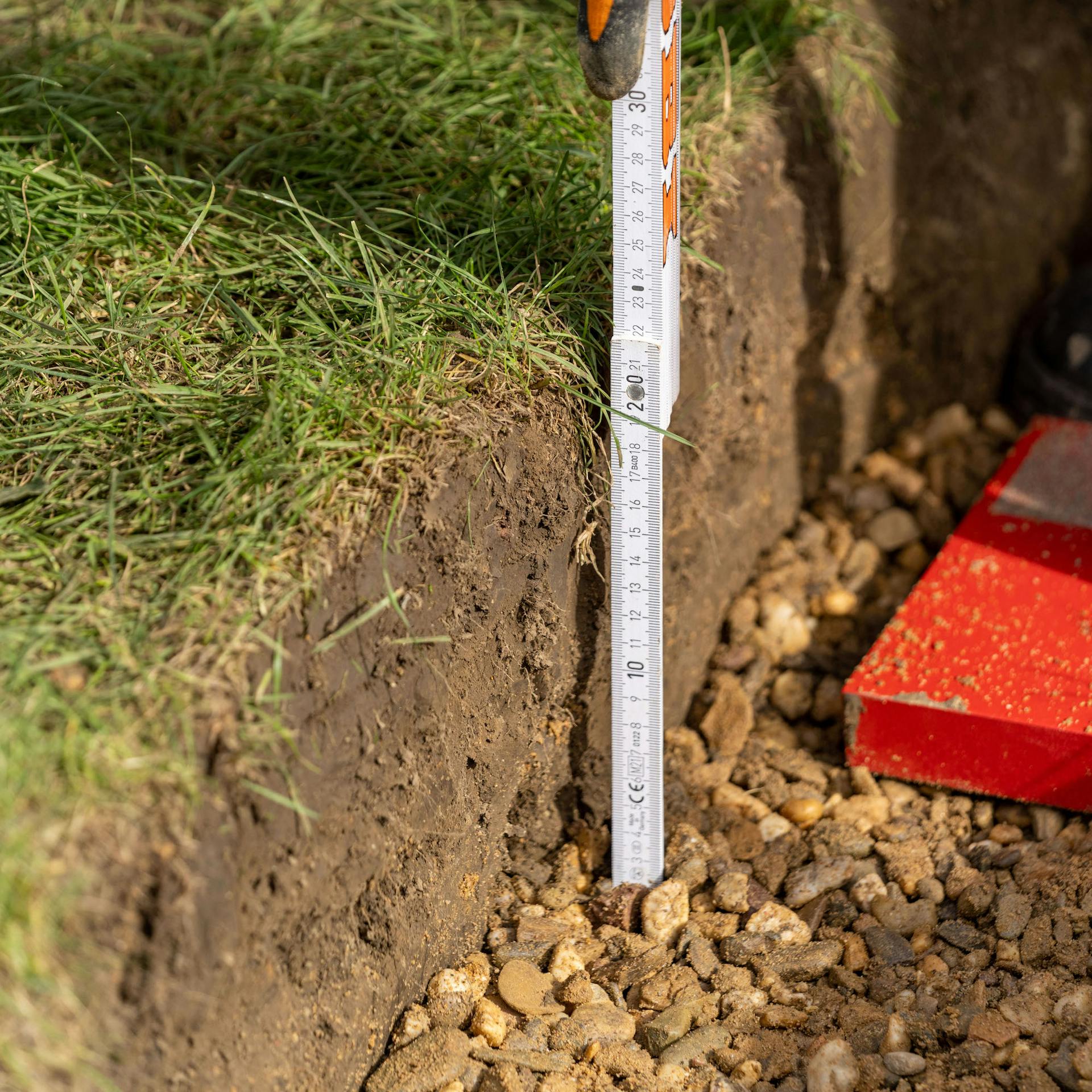 Mann hält Zollstock in Grube