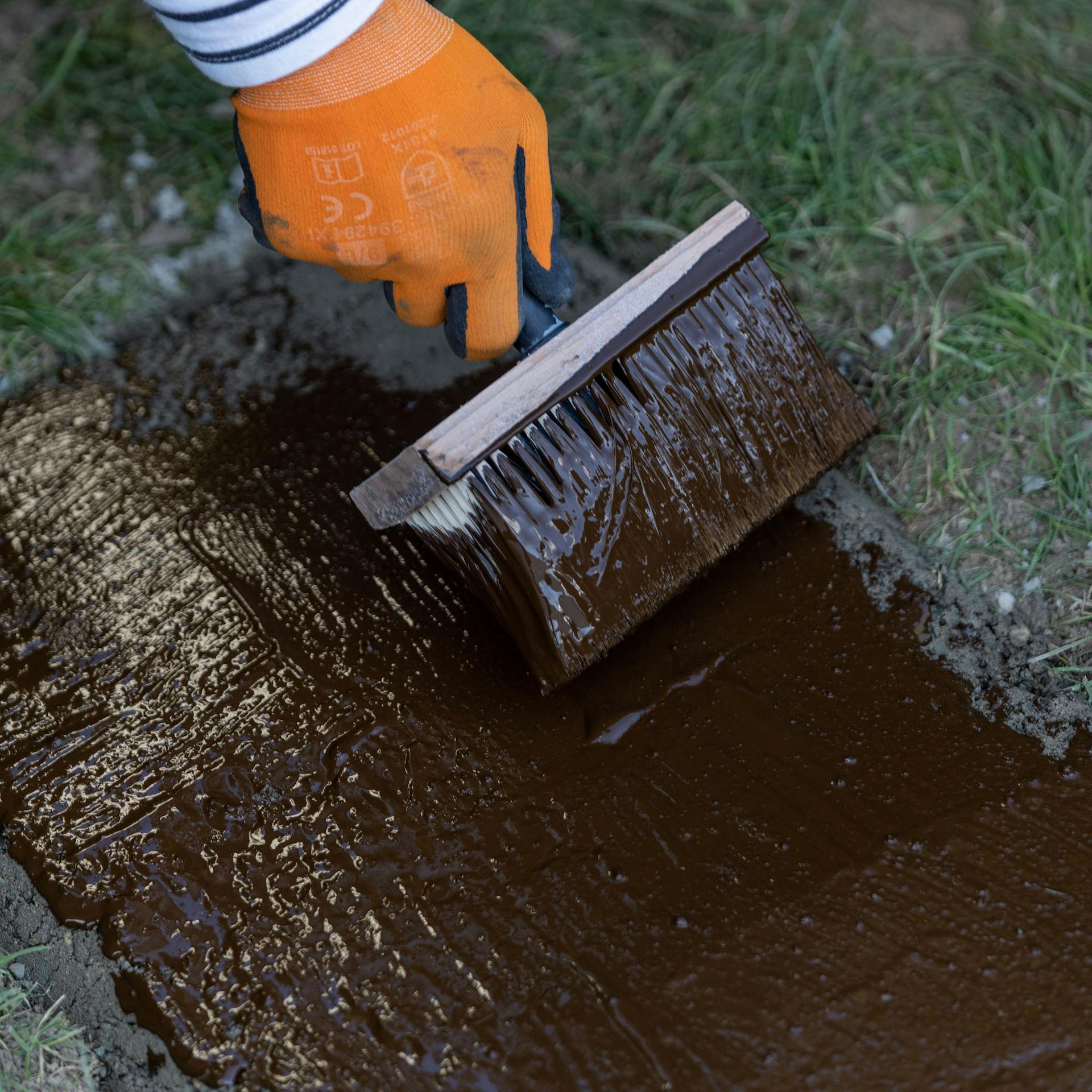 Bitumen wird mit Quast verteilt