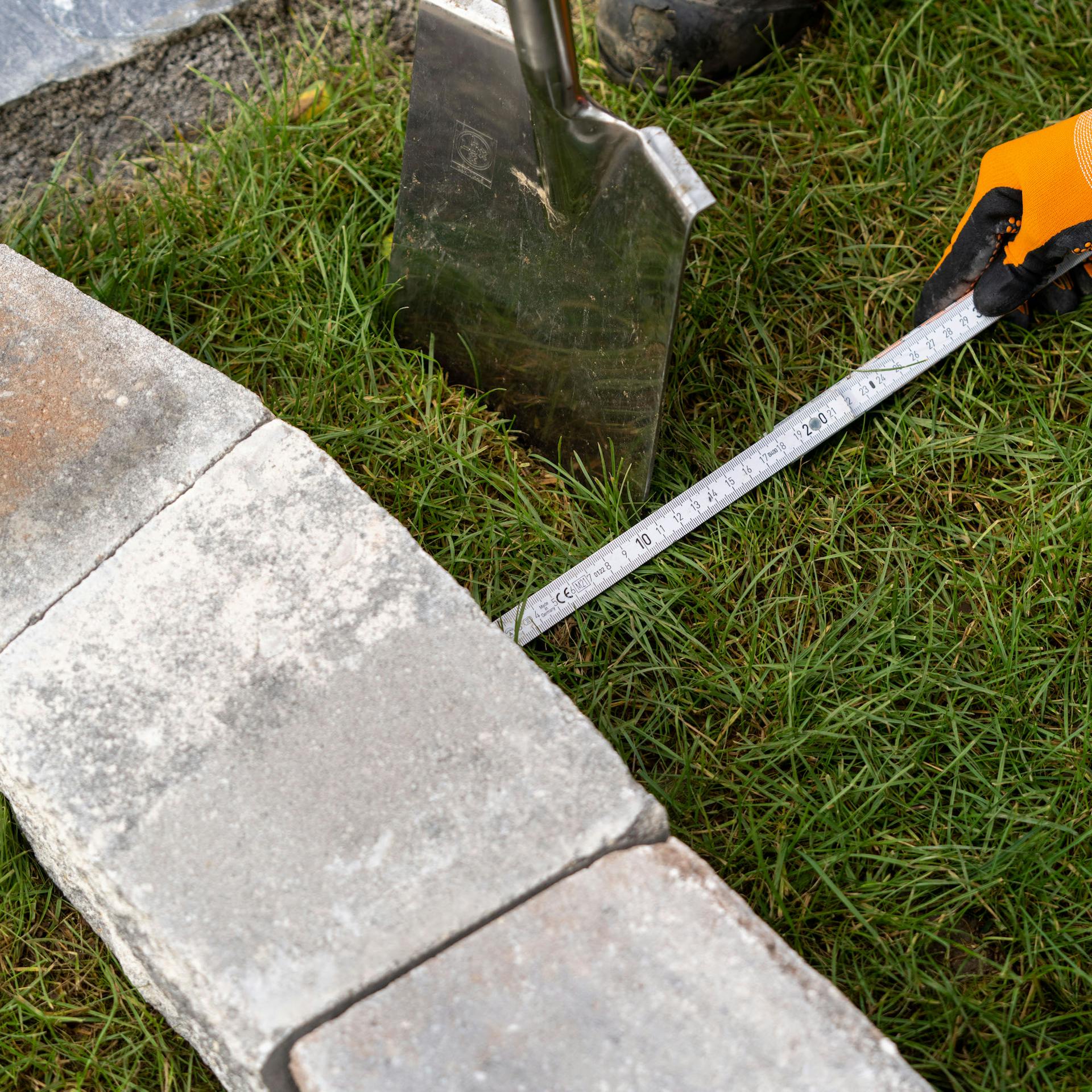 Person hält Maßband an Mauersteine