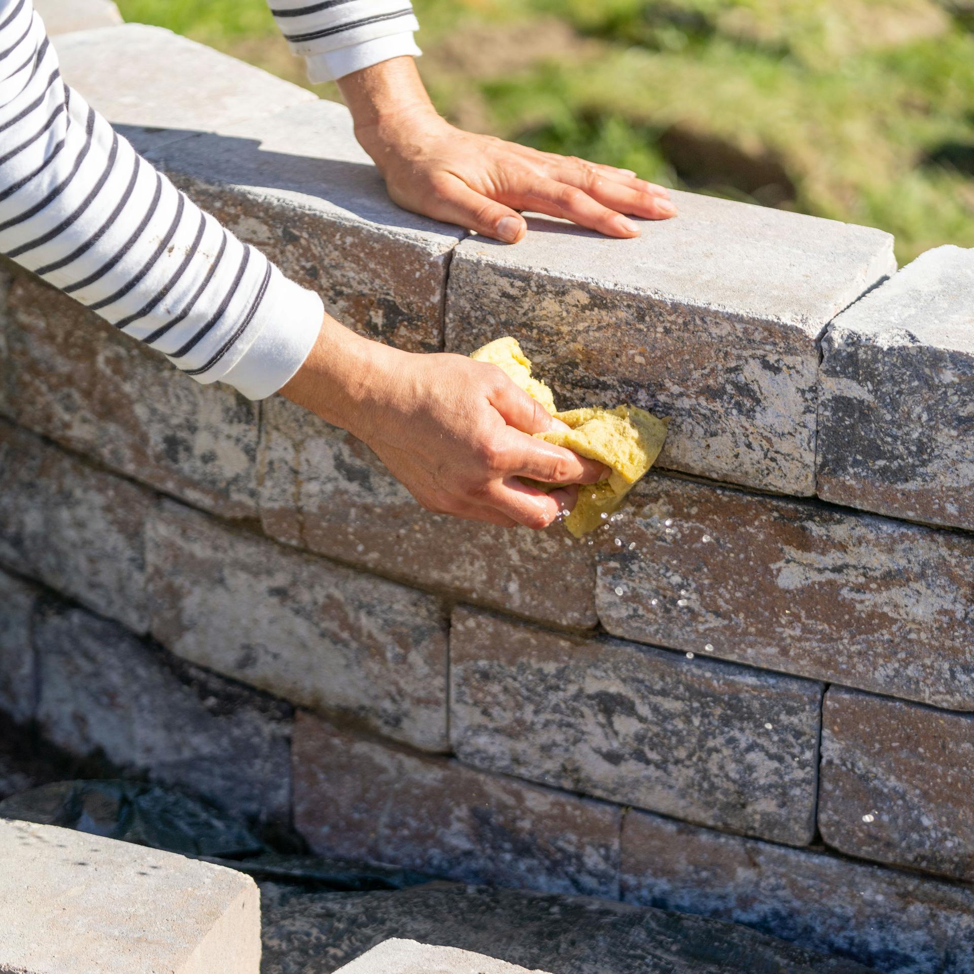 Hand wischt Steine einer Mauer ab