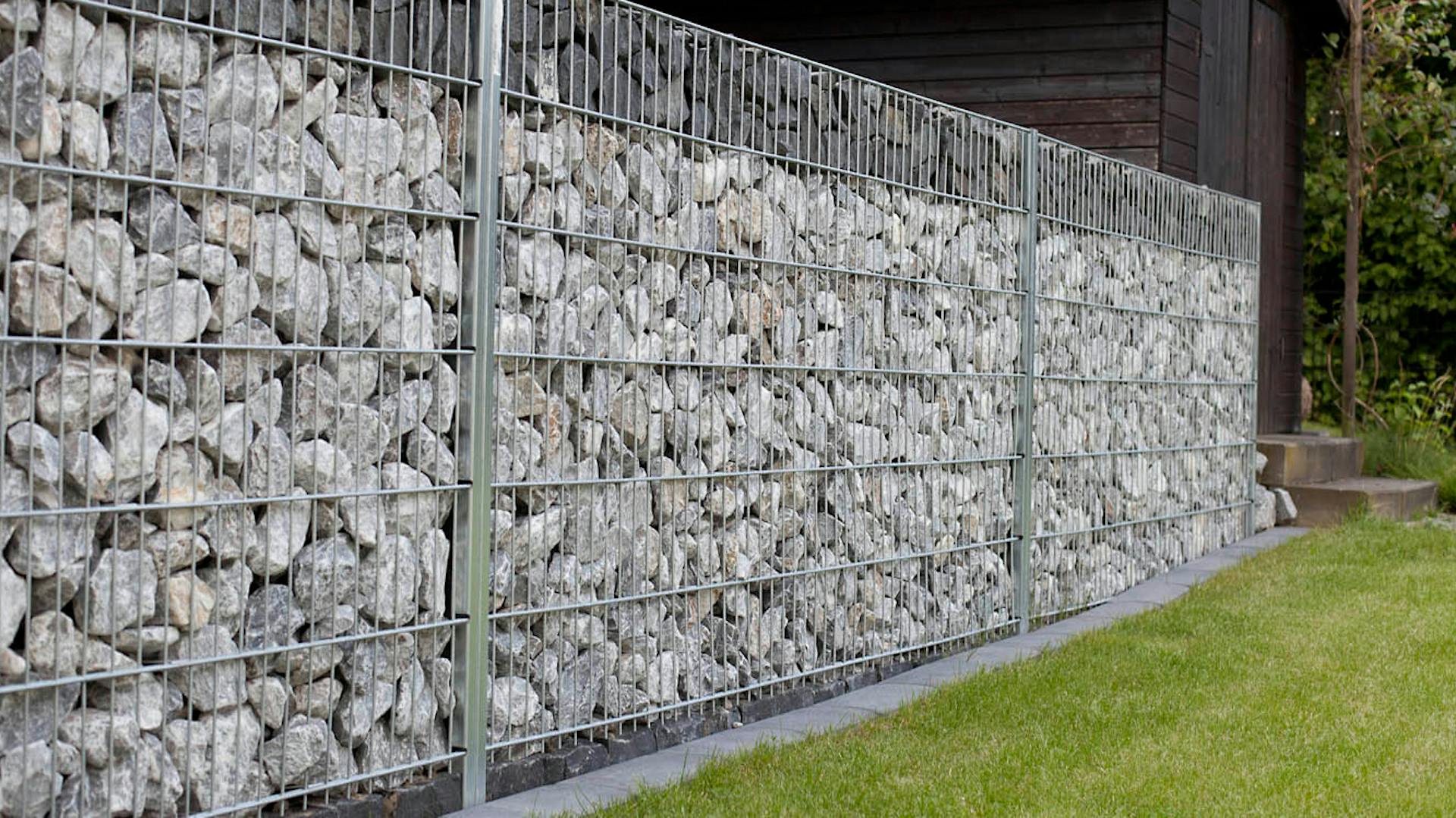 Mit grauen Steinen befüllte Gabionen bilden Mauer