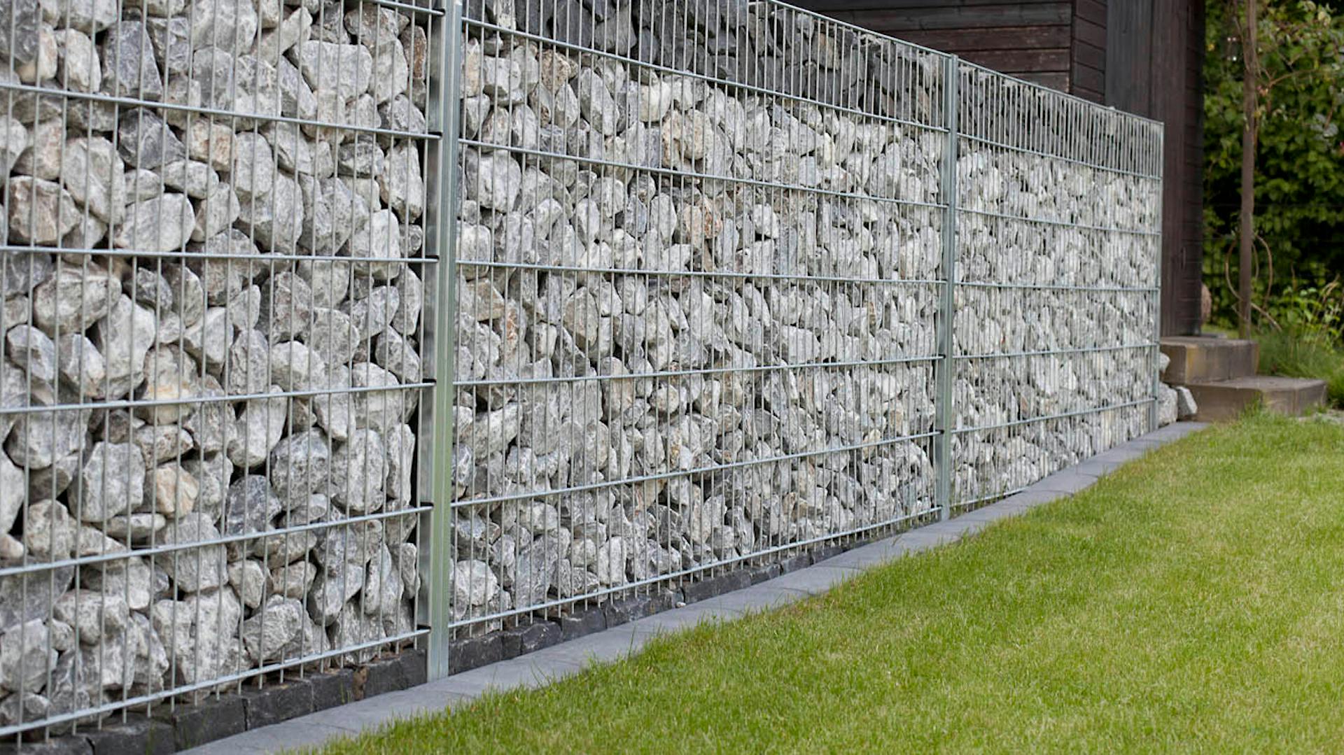 Mit grauen Steinen befüllte Gabionen bilden Mauer