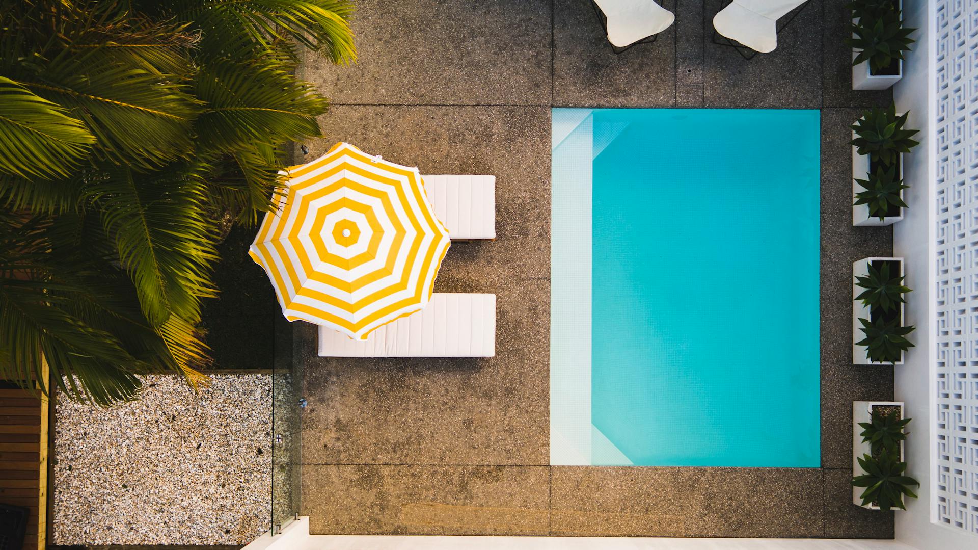 Rechteckiger Mini-Pool, Liegen und Sonnenschirm aus der Vogelperspektive.