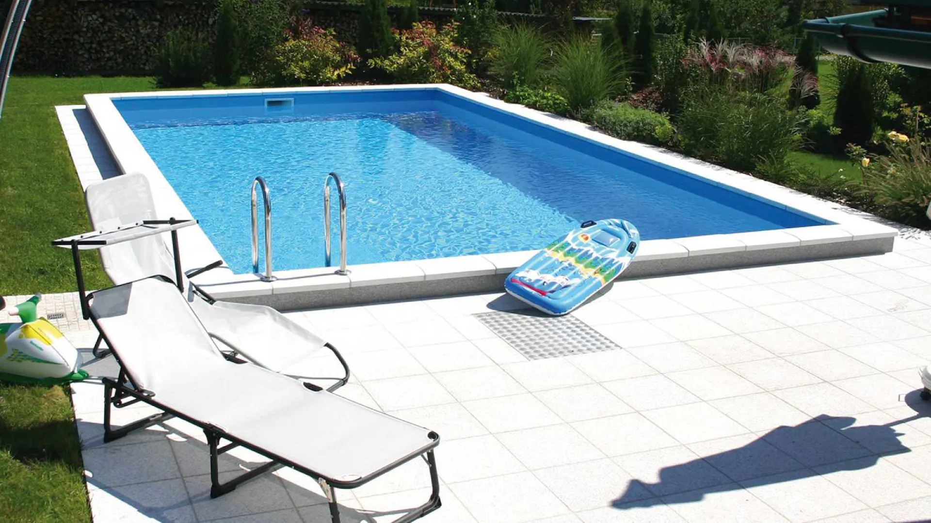 Eingebauter Pool im Garten neben Rasen, Terrasse und Sonnenliege