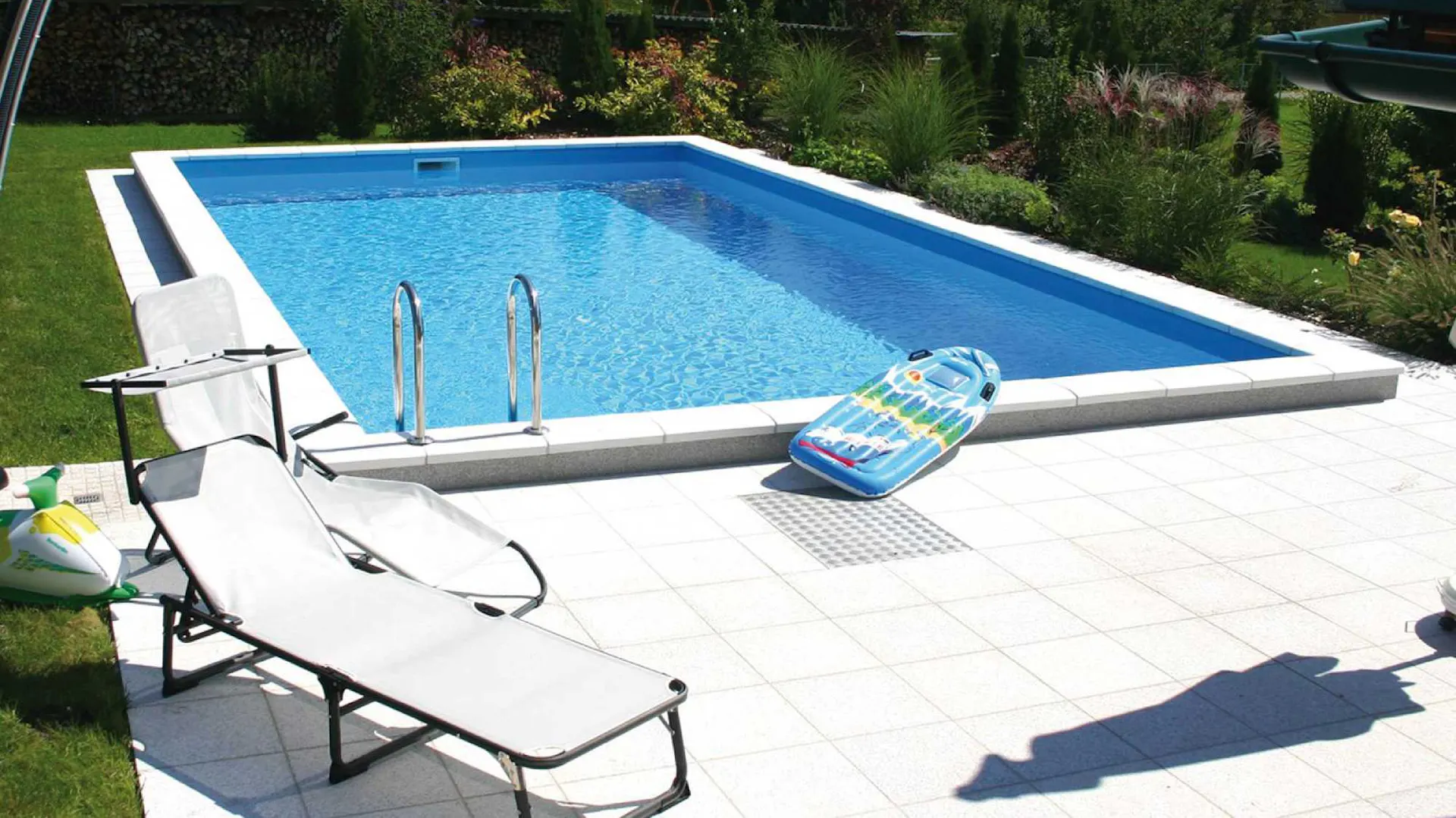 Eingebauter Pool im Garten neben Rasen, Terrasse und Sonnenliege