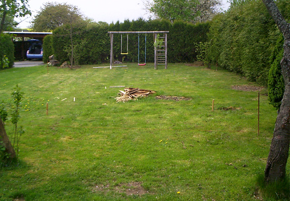 A kertben a gyepen fából készült karókkal jelölték ki a medence területét.