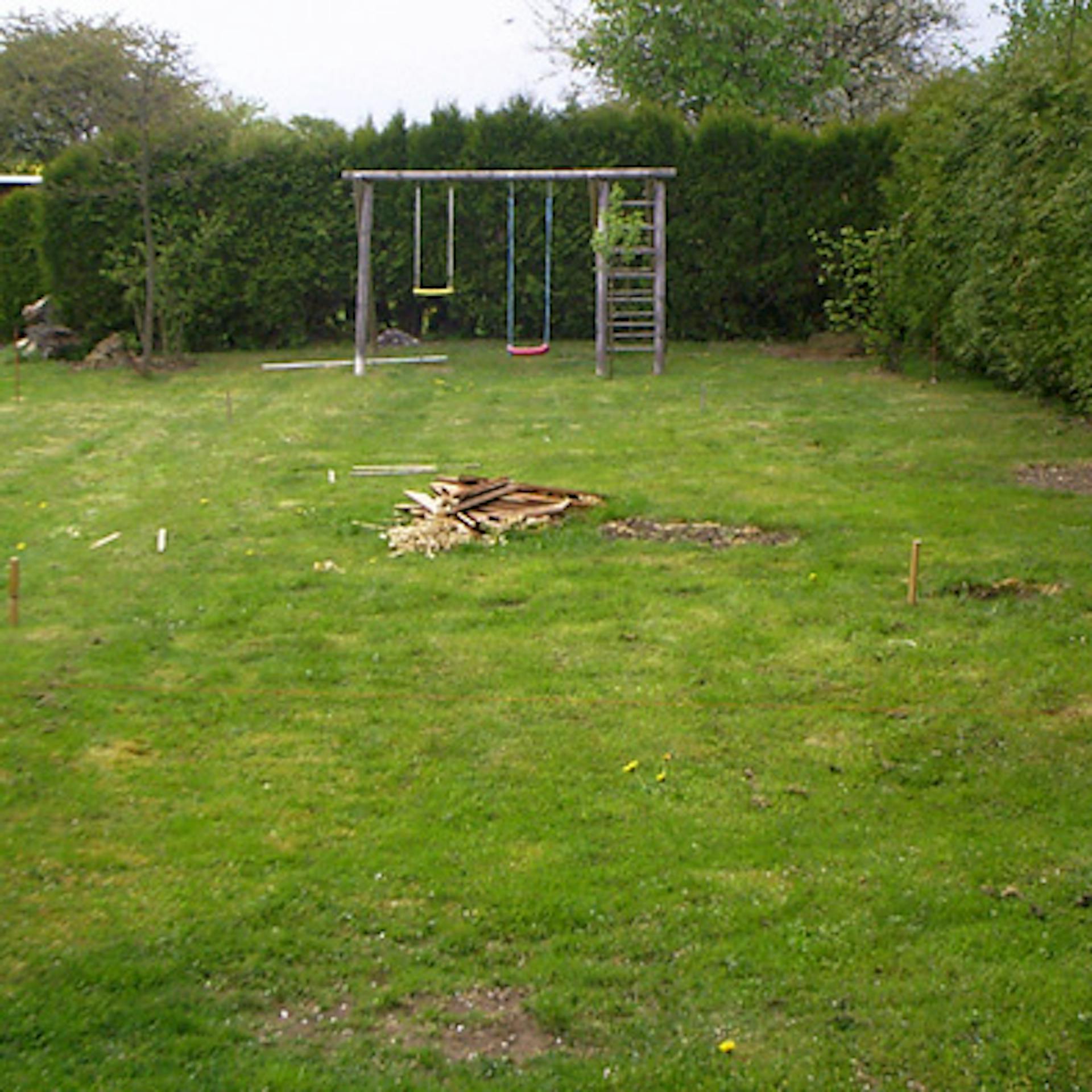 A kertben a gyepen fából készült karókkal jelölték ki a medence területét.