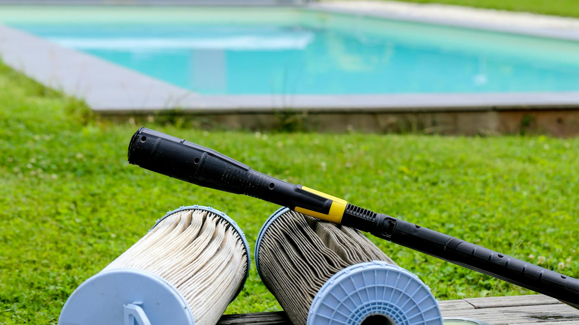 Cartucce filtro per piscina su un ripiano in legno davanti alla piscina in giardino