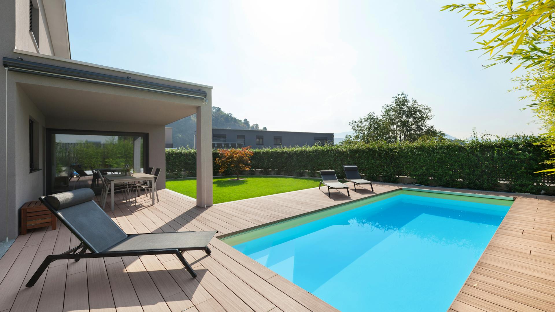 Einbaupool mit Holzumrandung neben Haus