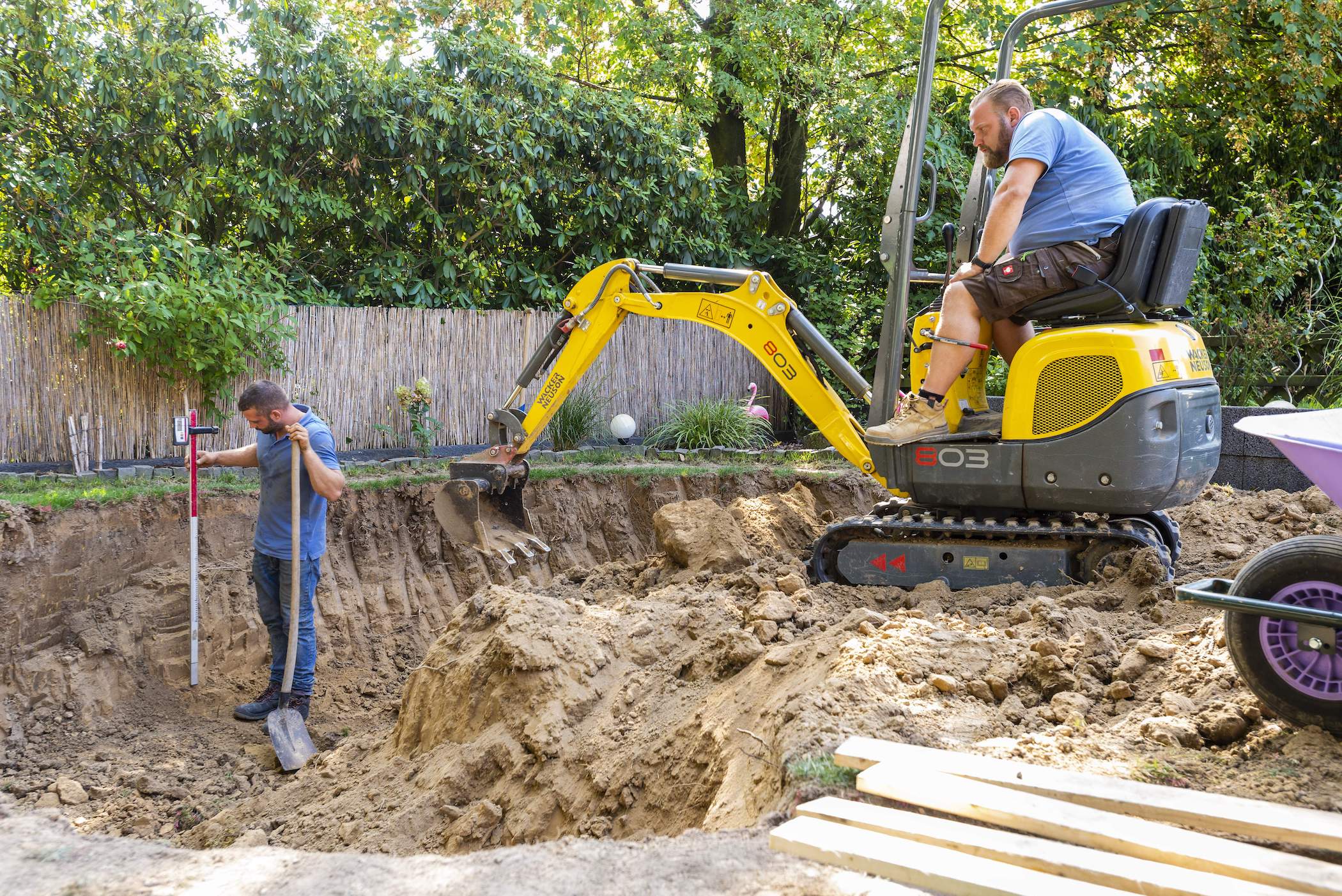 Handwerker heben eine Grube mit einem Bagger aus