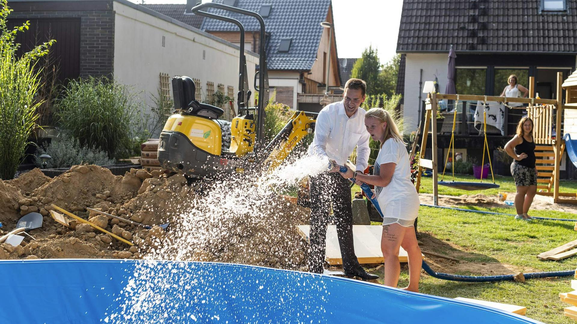 Zwei Personen füllen Wasser in den Pool.