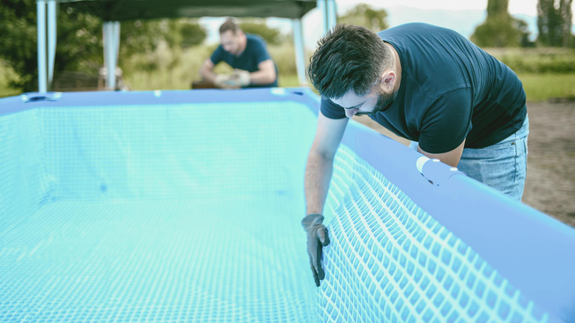 Jemand prüft einen Aufstellpool auf Beschädigungen.