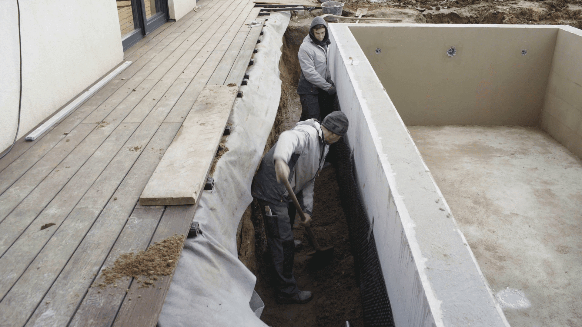 An der äußeren Beckenwand des Pools wird Erde aufgefüllt.
