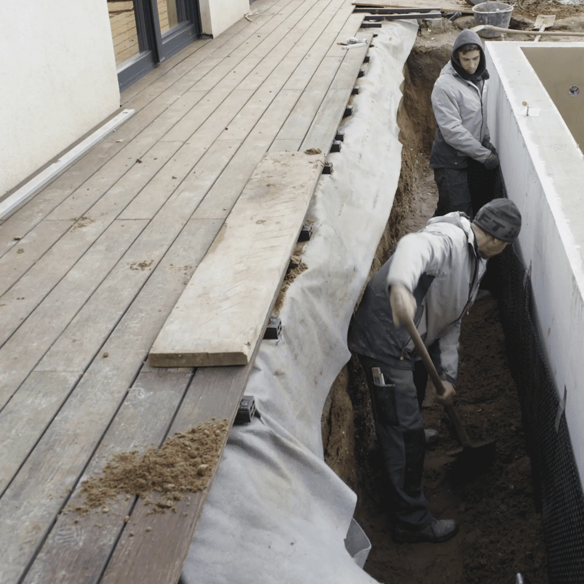 An der äußeren Beckenwand des Pools wird Erde aufgefüllt.
