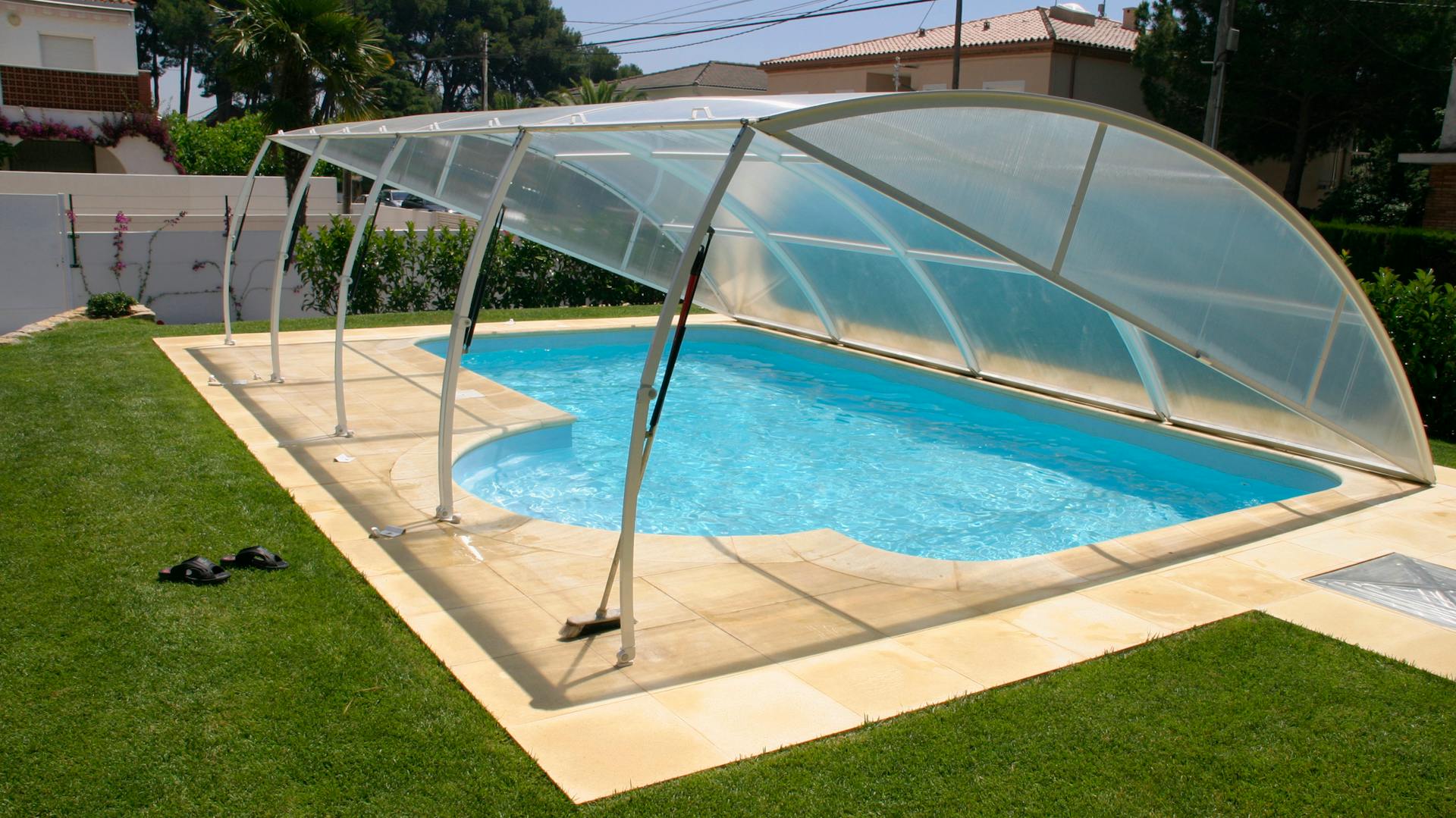 Geöffnete, festinstallierte Poolüberdachung über ebenerdigem Gartenpool