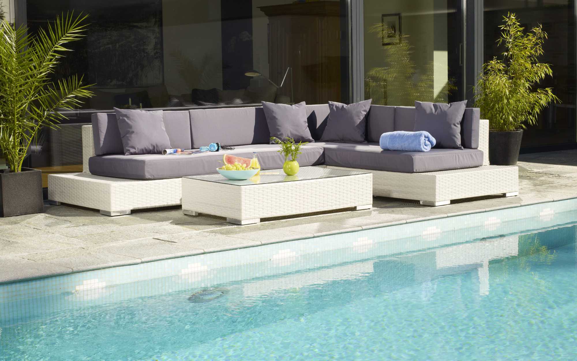 Pool mit Steinumrandung und Lounge-Gartenmöbeln vor Haus