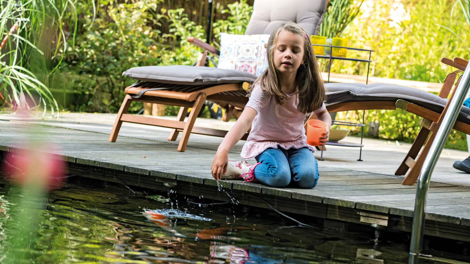 Junges Mädchen sitzt am Schwimmteich