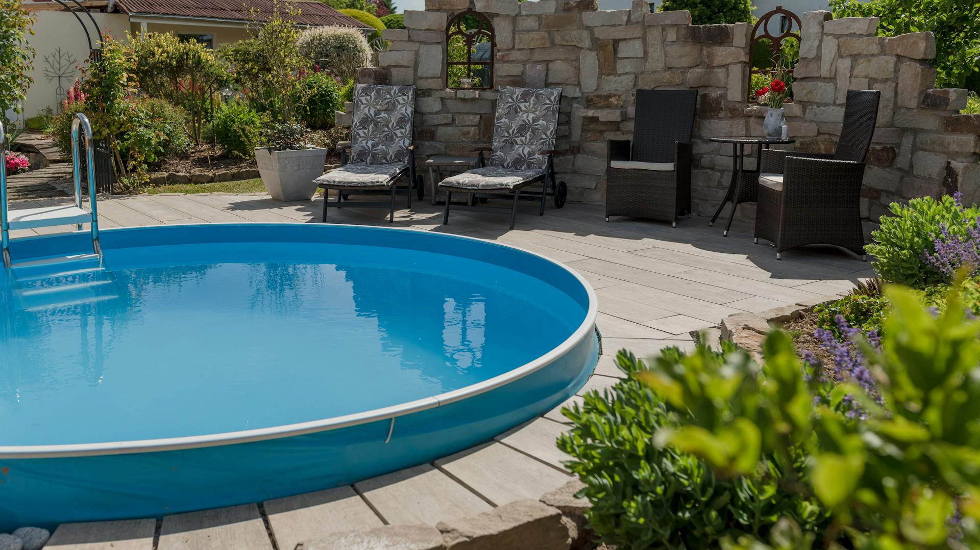 Piscina con fendivista e mobili da giardino