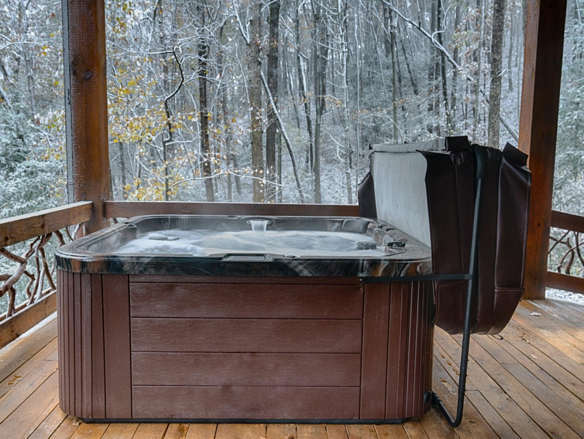 Offener Whirlpool auf Holzterrasse mit winterlichem Wald im Hintergrund