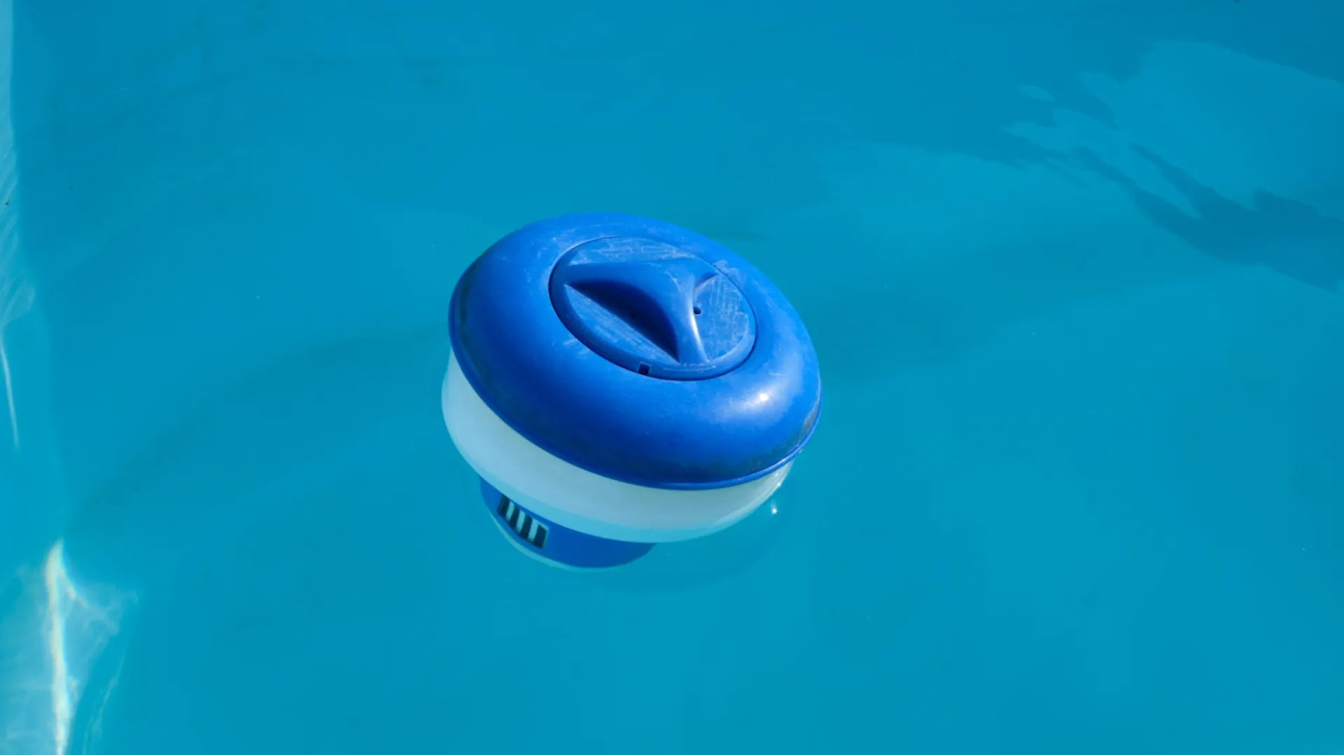 Blauer Chlortablettenspender schwimmt auf Wasseroberfläche.