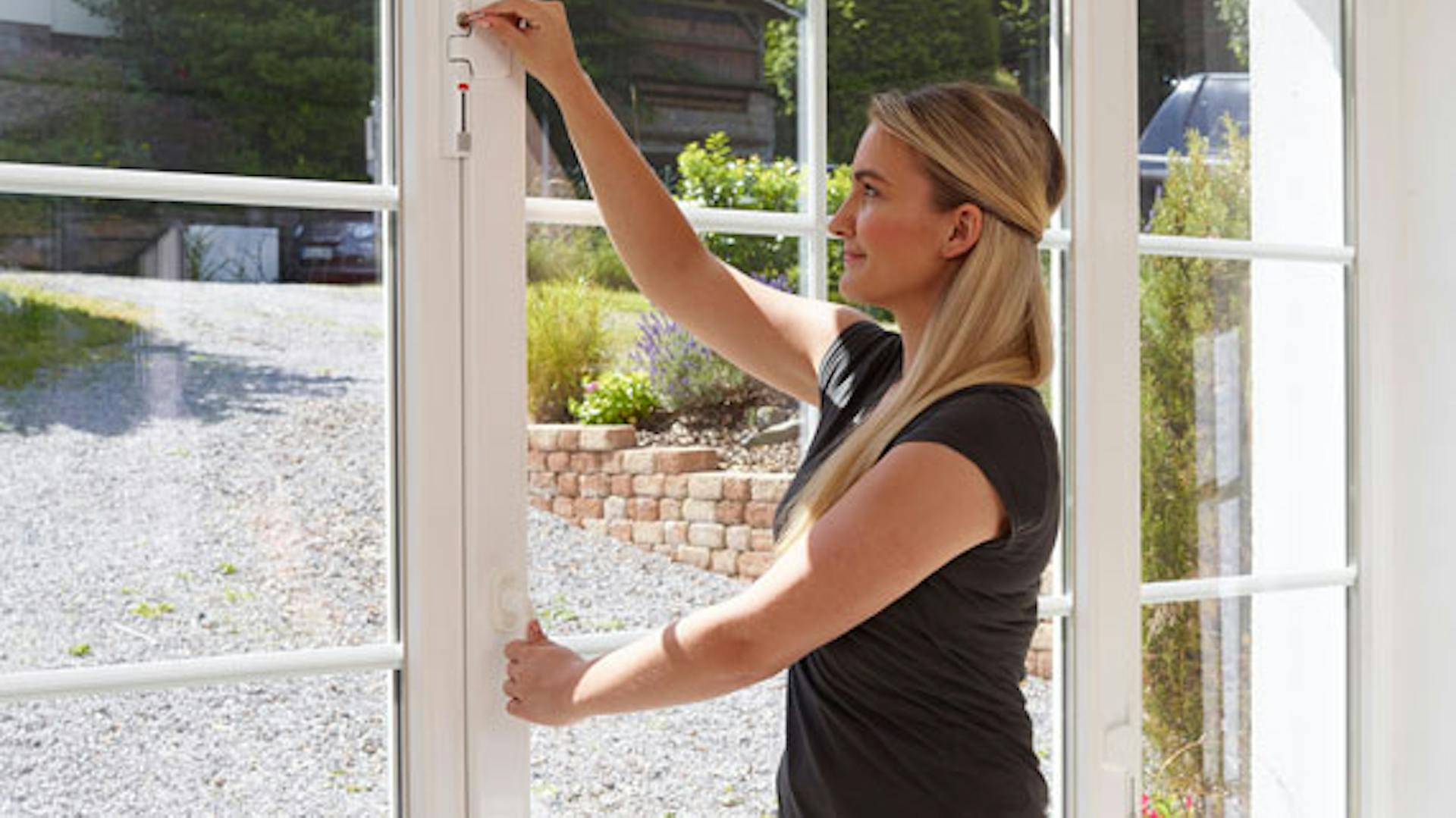 Frau schließt Fenstersicherung an Terrassentür aus Glas