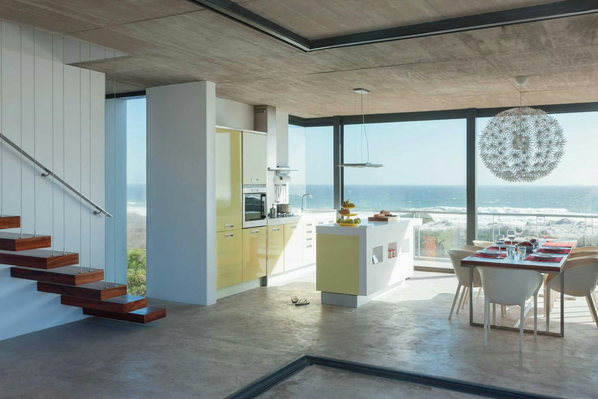Ampio e luminoso spazio con cucina e tavolo da pranzo con finestre a pavimento e vista sul mare