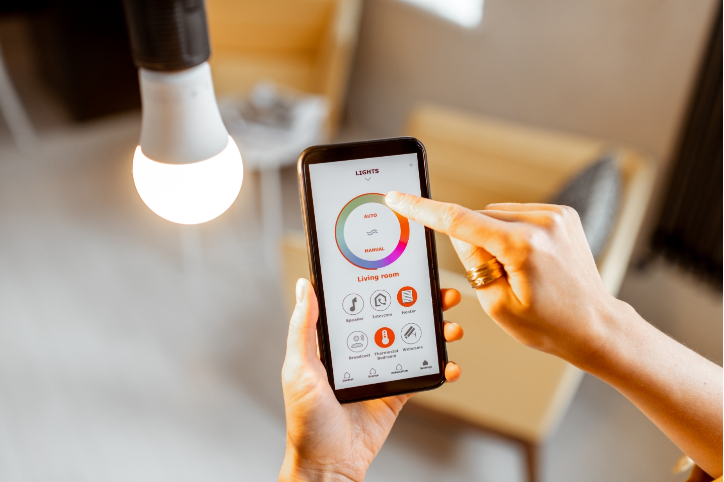 Person bedient Lampe mit Smartphone über Smart Home-App