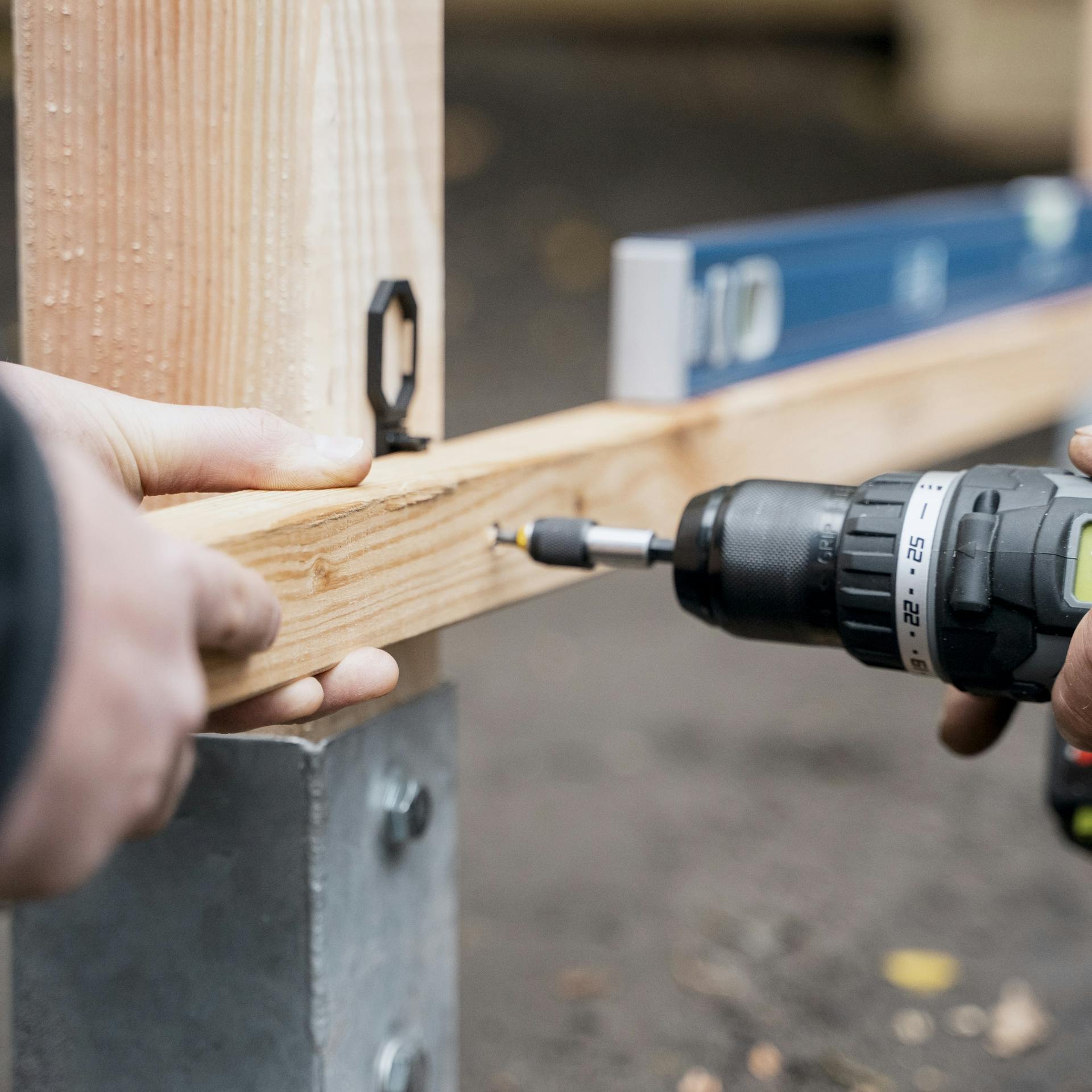 Jemand bringt Querlatten mit einer Bohrmaschine an.