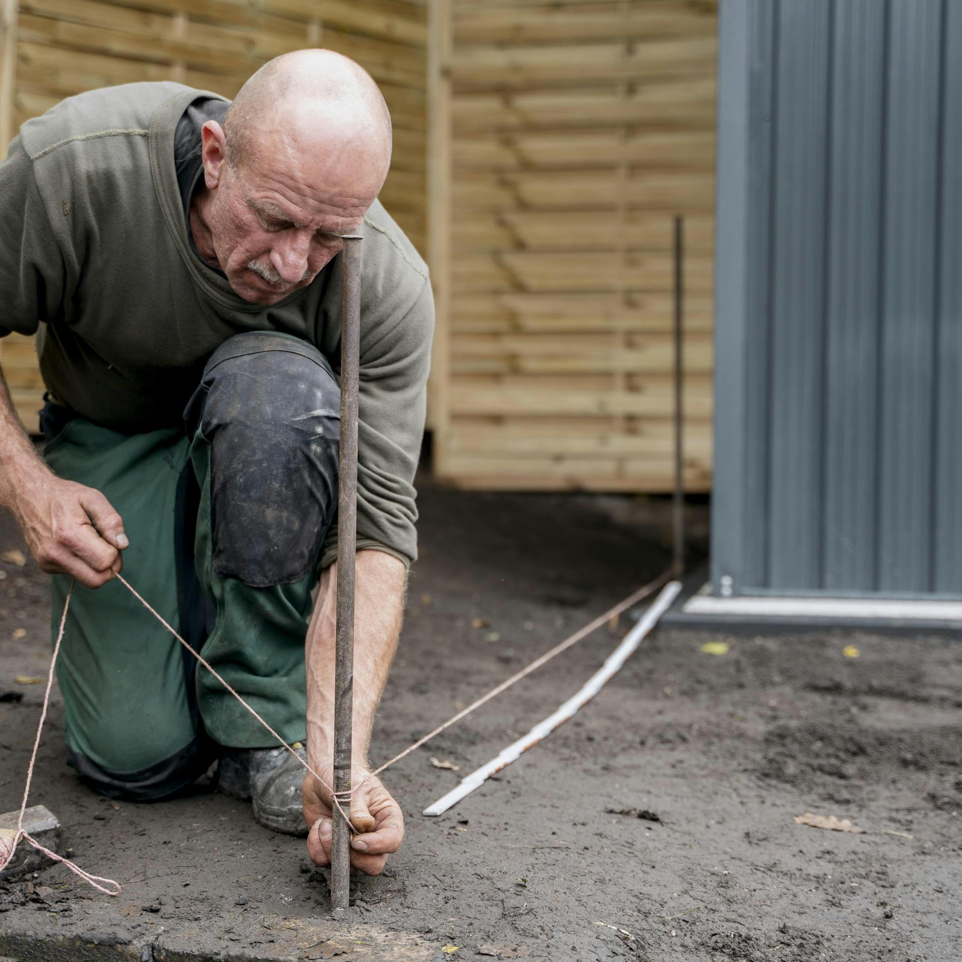 Ein Mann setzt mit Schnurnagel und Maurerschnur das Schnurgerüst.