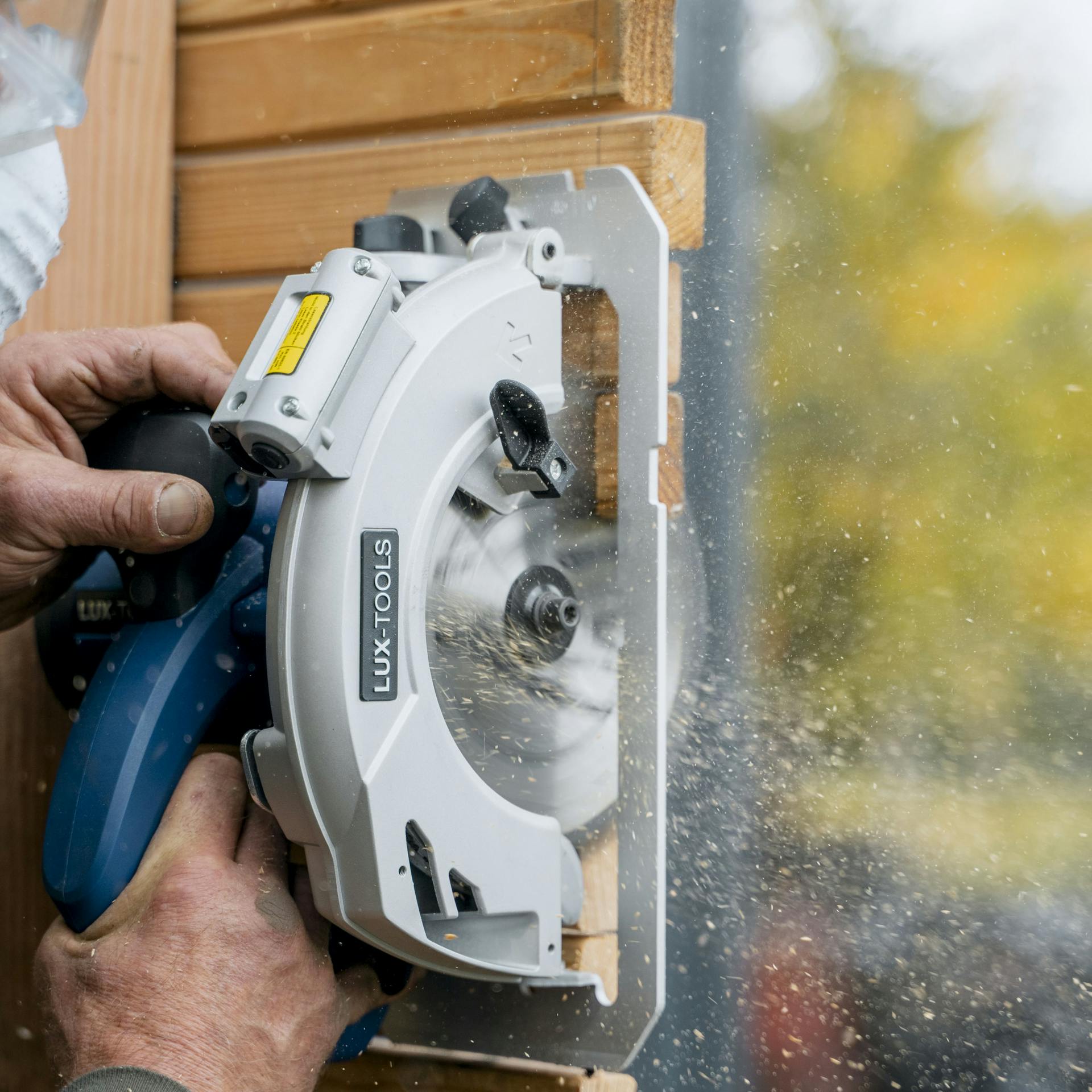 Ein Mann längt die Querlatten mit einer Säge ab.