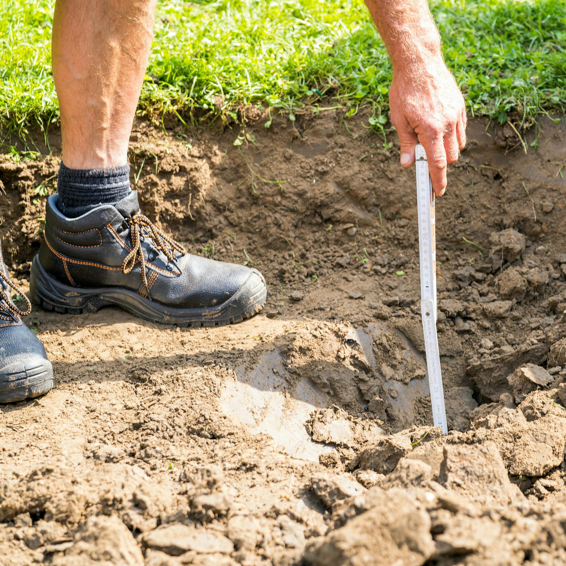 Mit dem Zollstock wird die Tiefe der Grube kontrolliert.