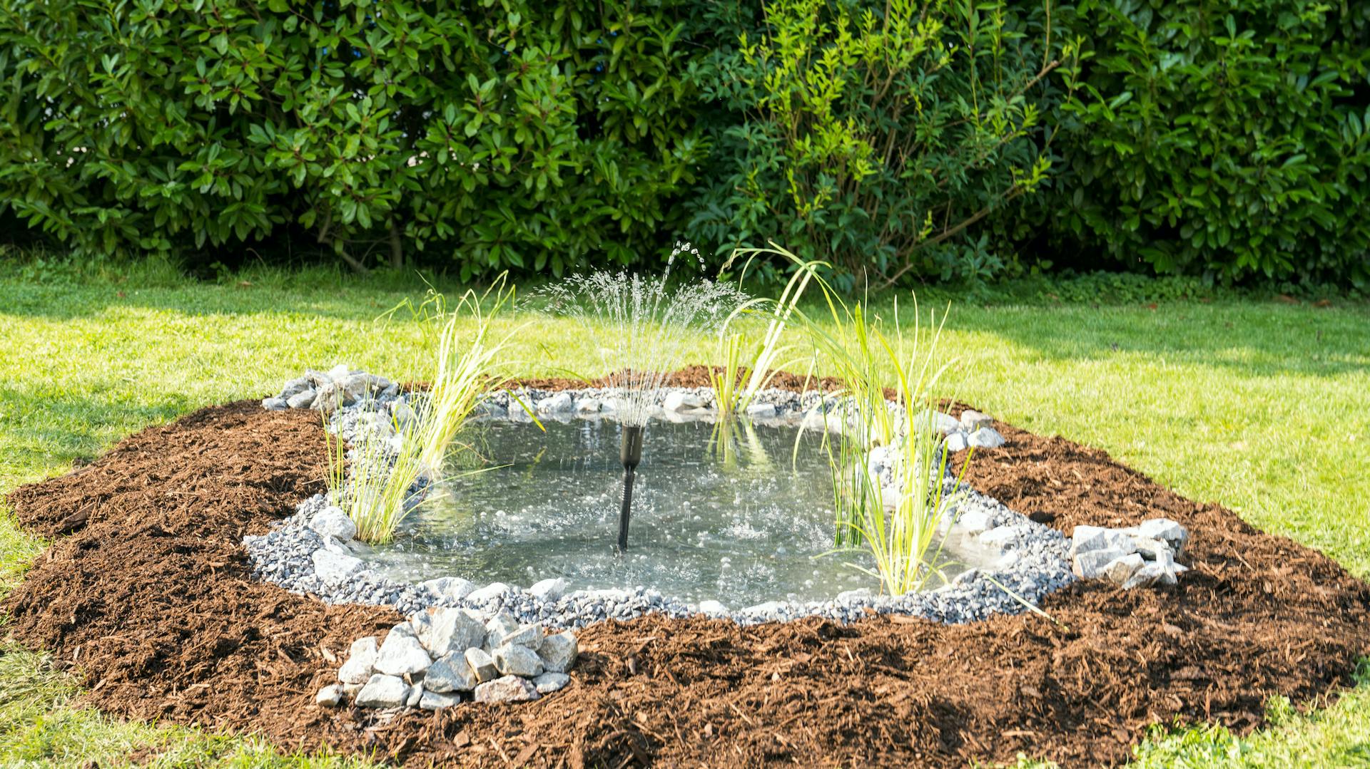 Mit Pflanzen und Steinen umgebener Fertigteich