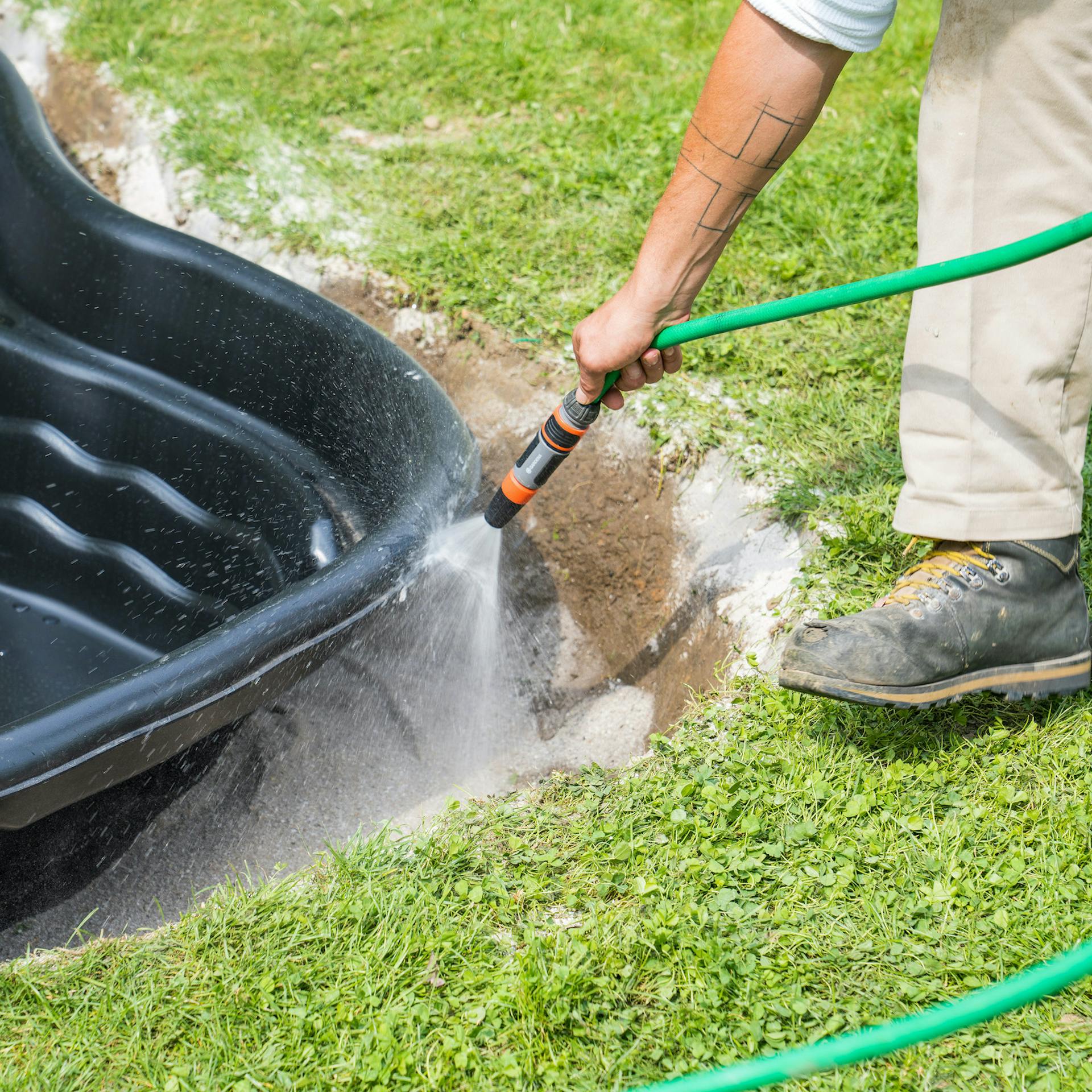 Sand wird mit Gartenschlauch gewässert