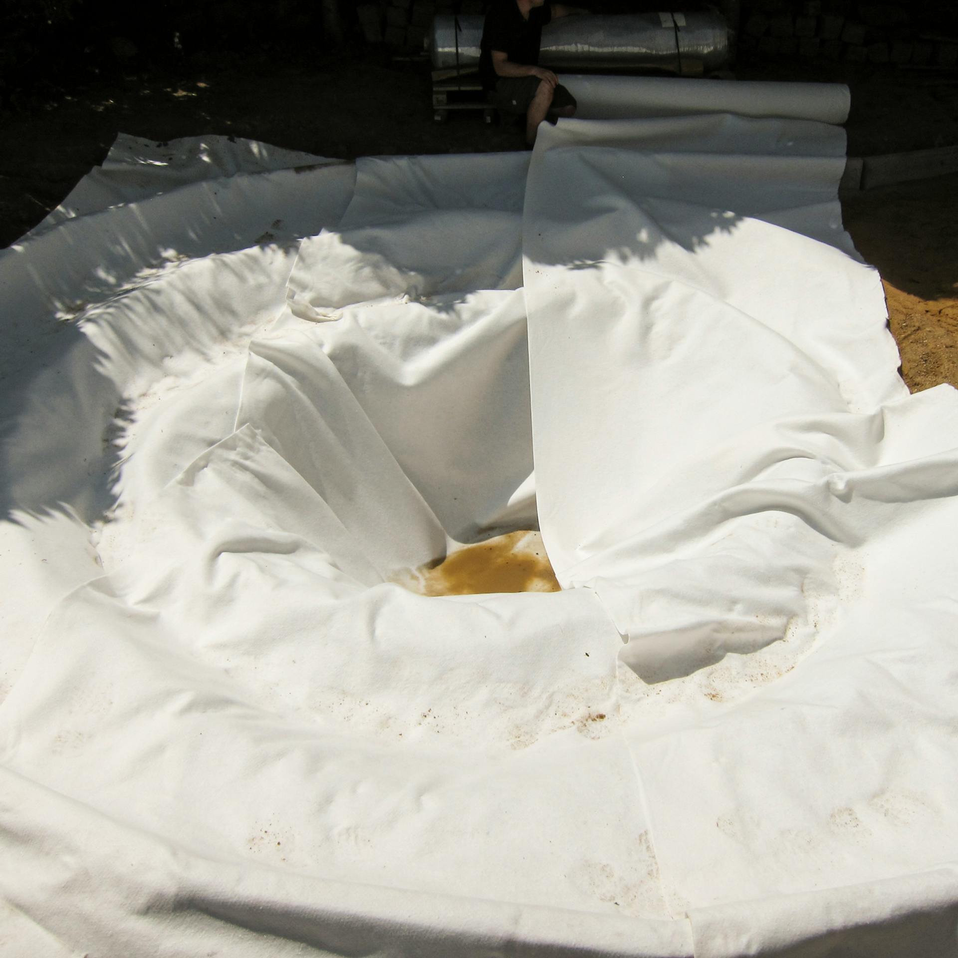 Geotextília kiterítése a tómederbe.