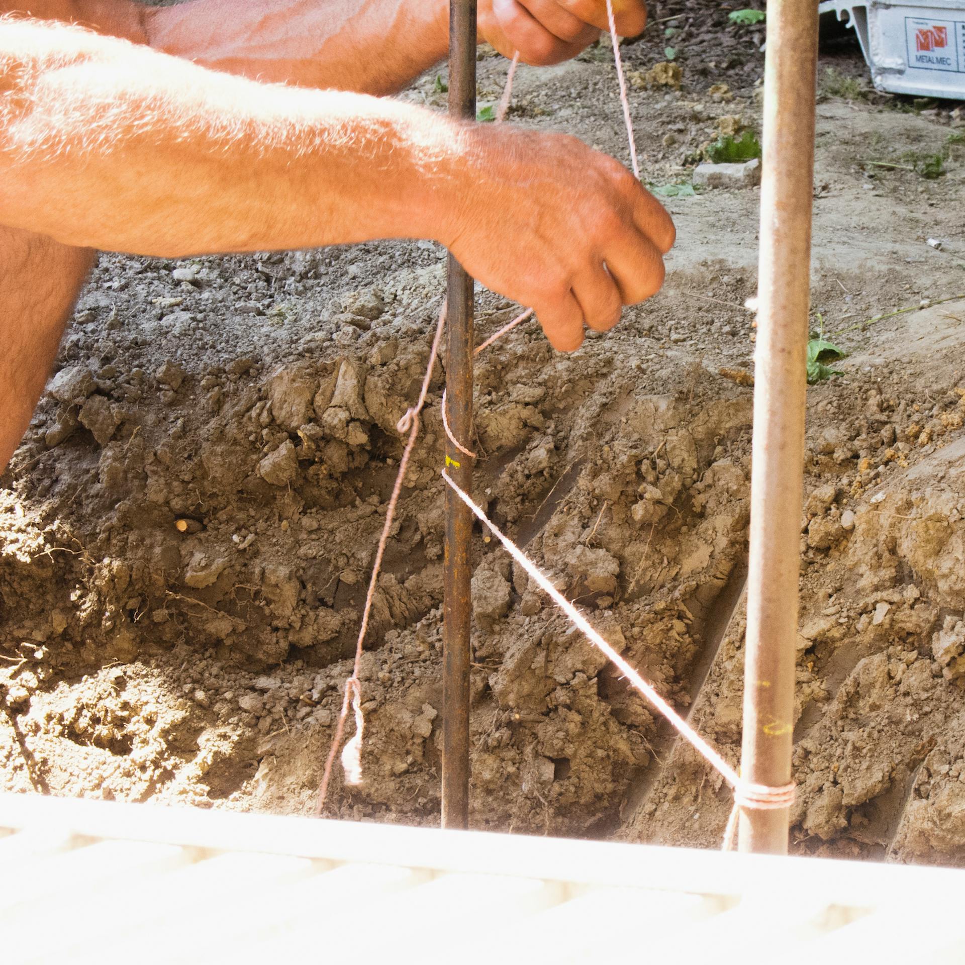 Munkás körbefűzi a zsinórt a vaskaróra.