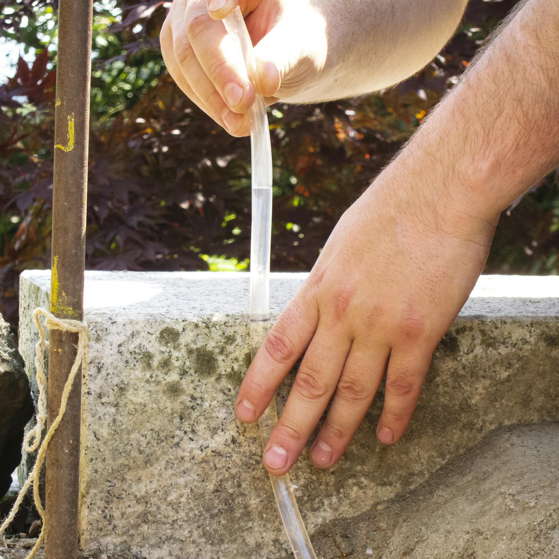 Schlauchwasserwaage wird an Kantenstein angehalten.