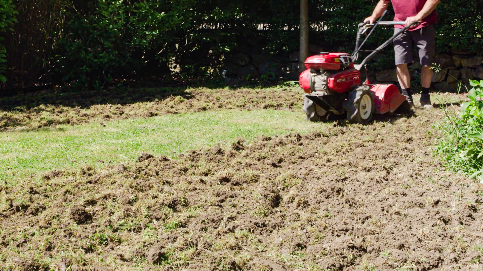 Mann mäht den Rasen auf einer großen Grünfläche.
