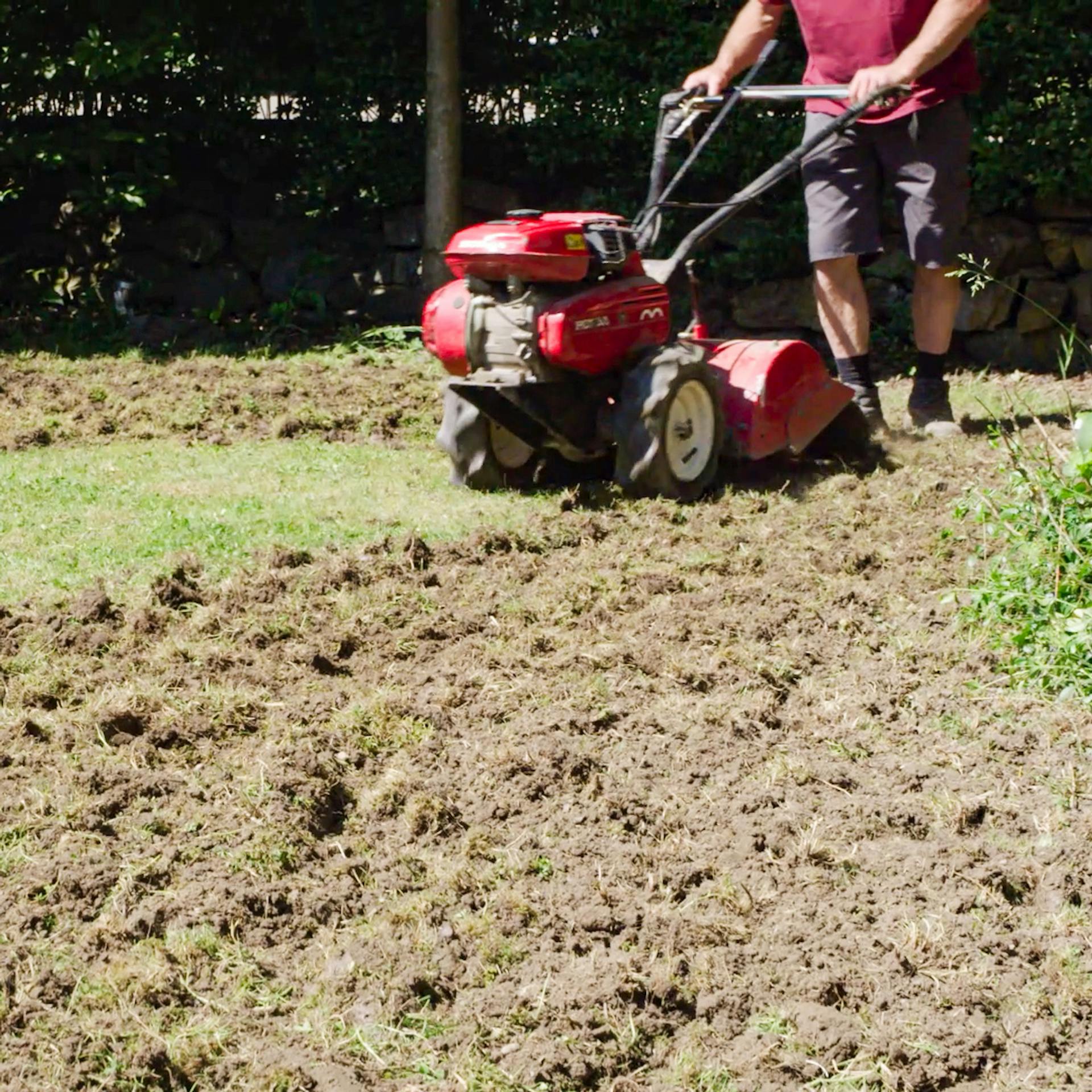Férfi füvet nyír egy nagy zöld területen.