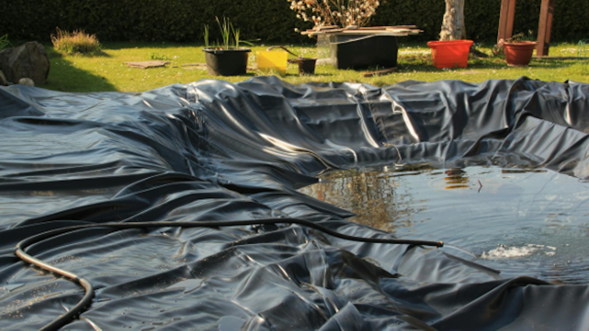 Gartenteich-Grube ist mit Teichfolie ausgelegt und wird über Gartenschlauch mit Wasser gefüllt.